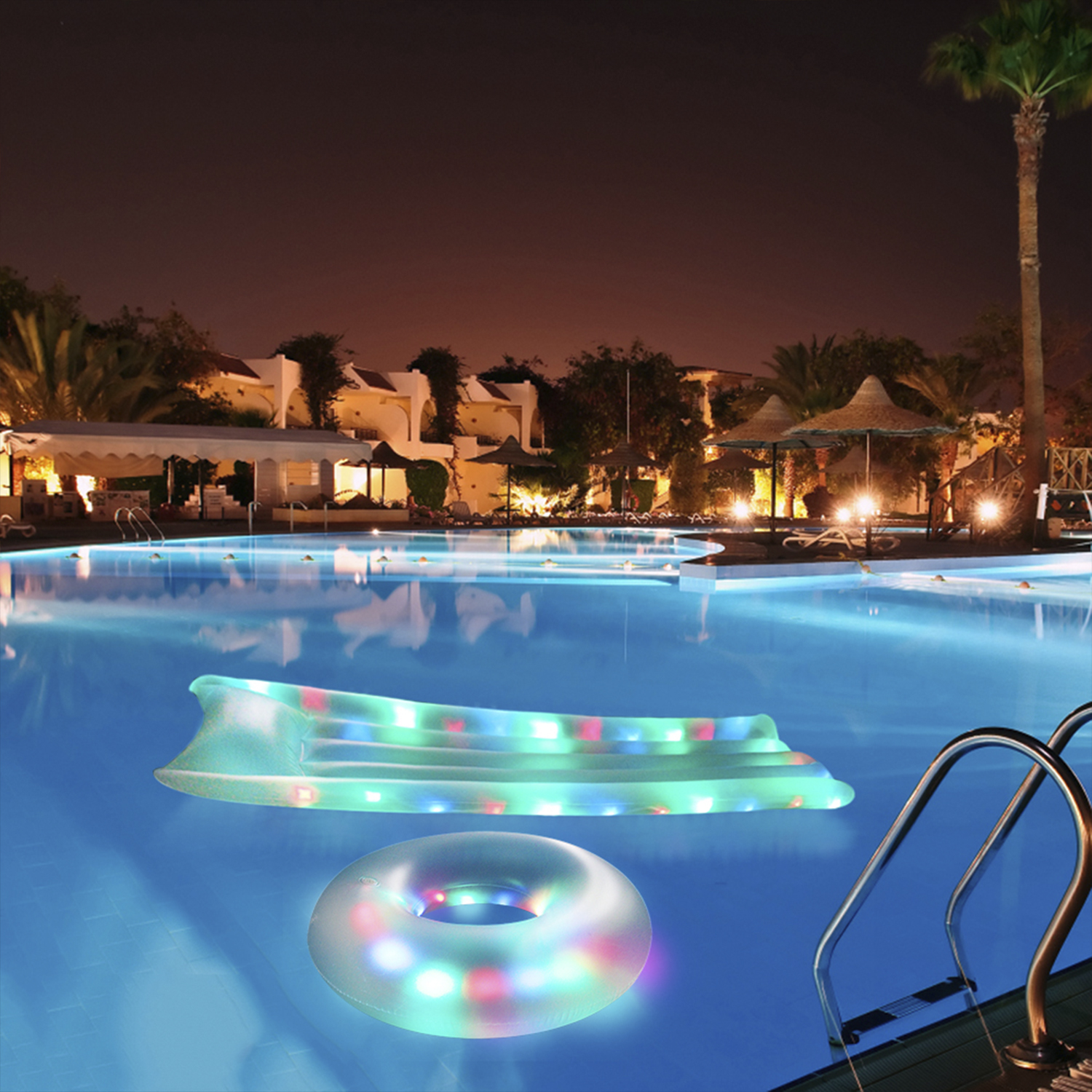 Scena notturna di una piscina con un gonfiabile galleggiante e un anello, illuminati da luci colorate.