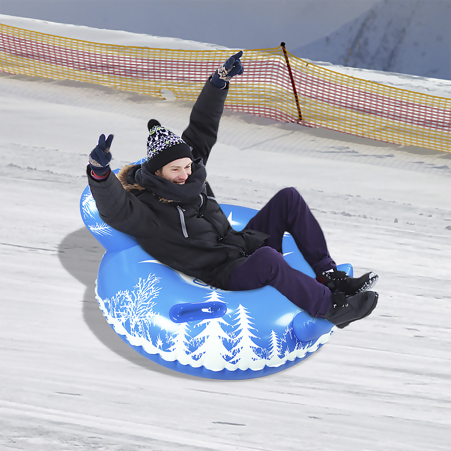 Persona deslizándose por una colina nevada en un tubo inflable azul, levantando los brazos.