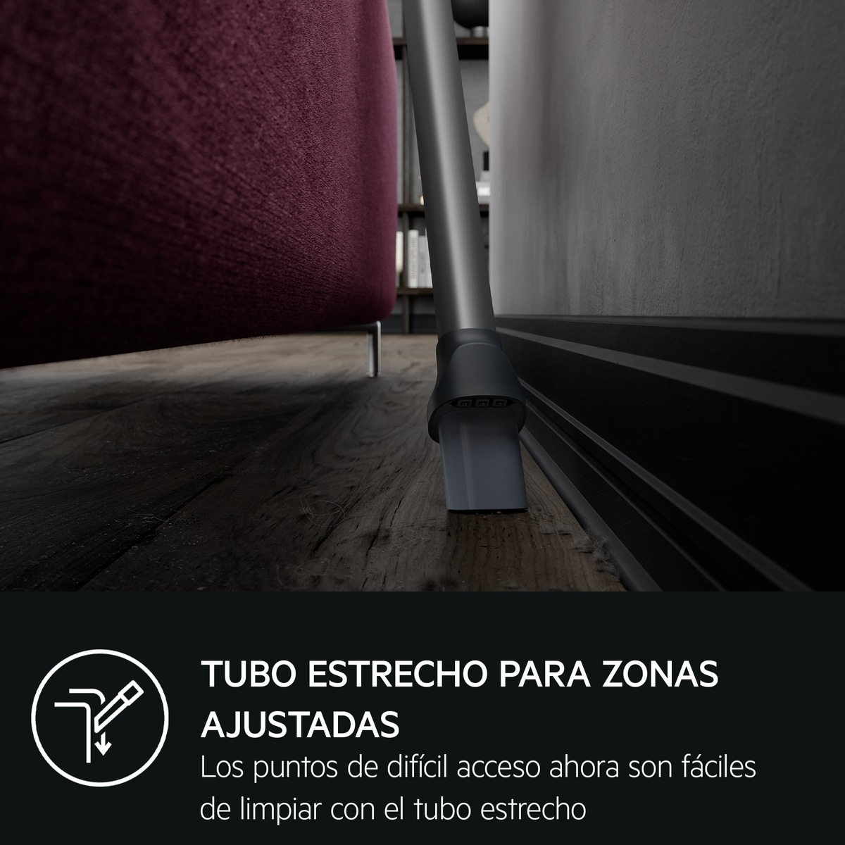 Cabezal de aspiradora limpiando cerca de una pared y un sofá.