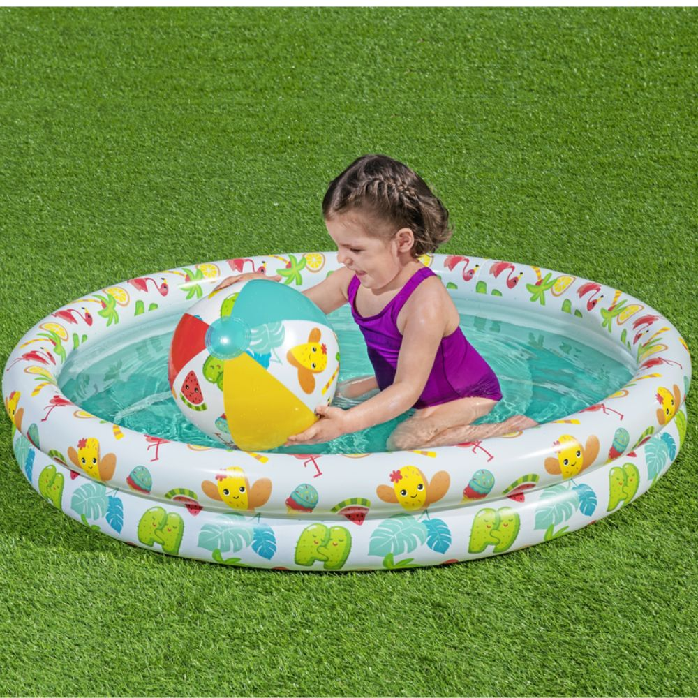 Une fille en maillot de bain violet avec un ballon de plage dans une piscine.