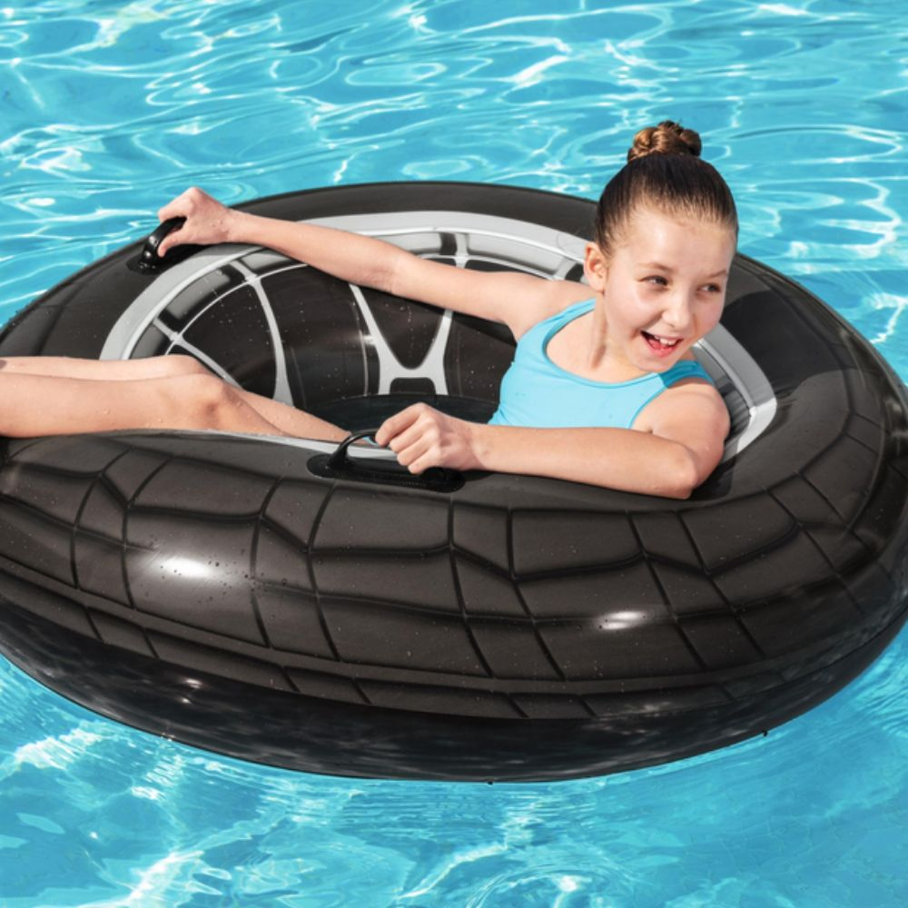A girl is in a black inflatable tire in the pool.