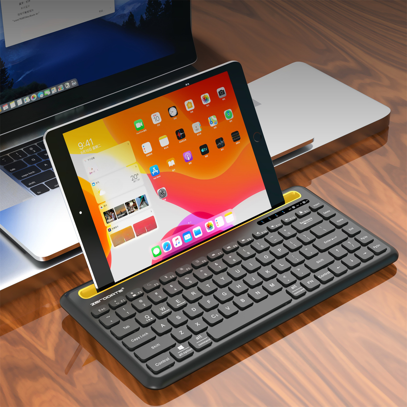 Eine schwarz-gelbe Tastatur mit Tablet und Laptop auf einem Holzschreibtisch.