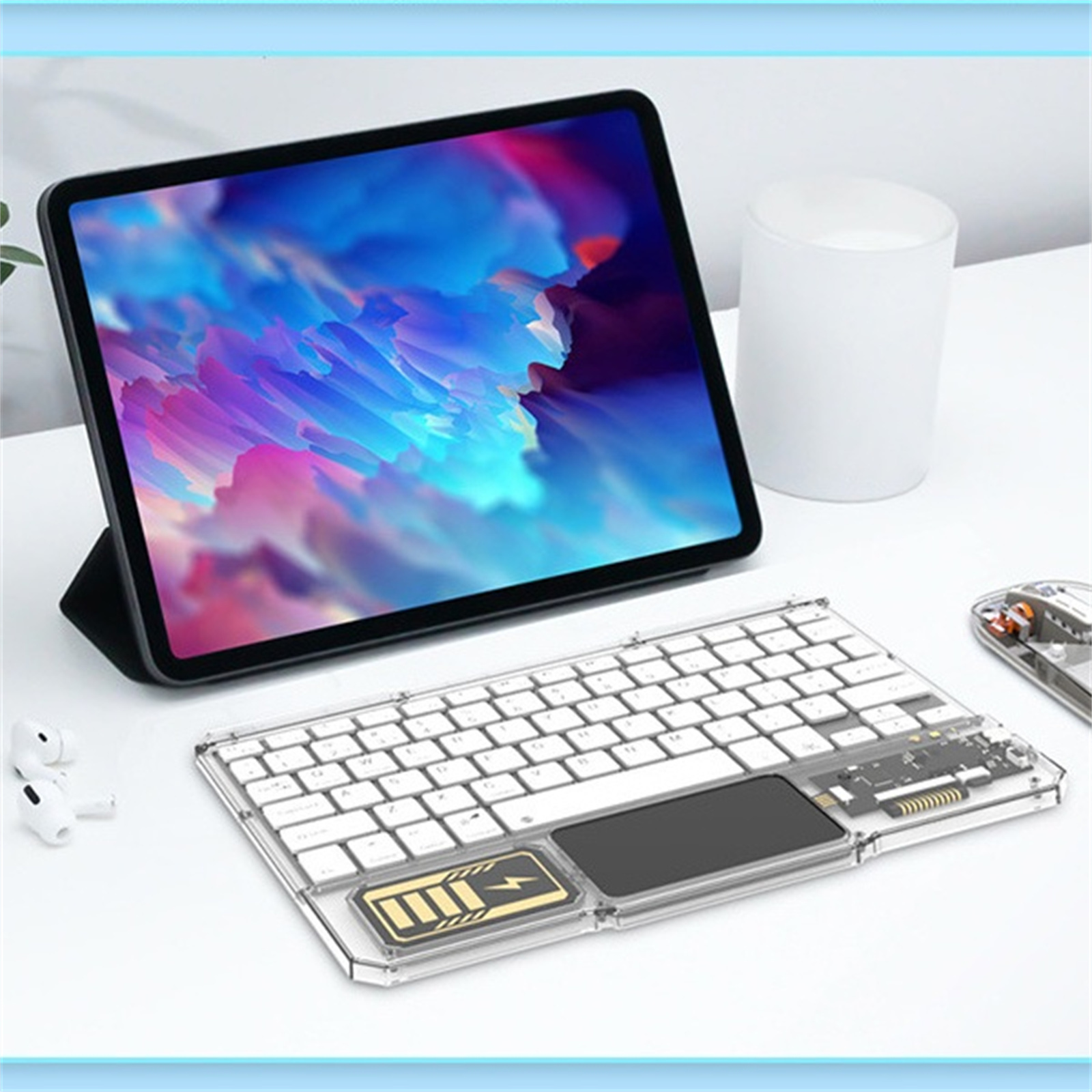 Tablet mit Tastatur und Touchpad. Weißer Becher und kabellose Ohrhörer.