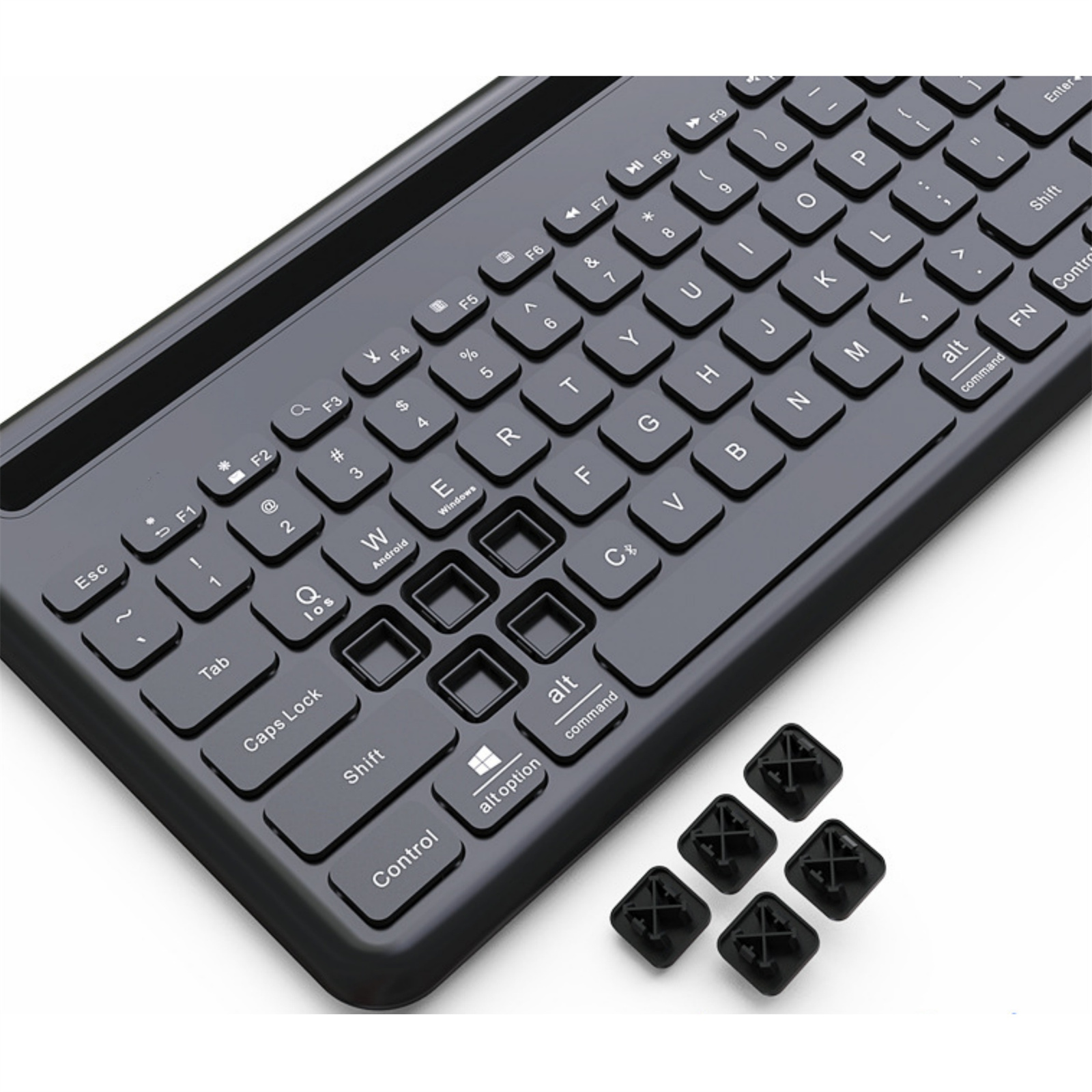 Schwarze Tastatur mit beschrifteten Tasten und mehreren Ersatz-Tastenkappen daneben.