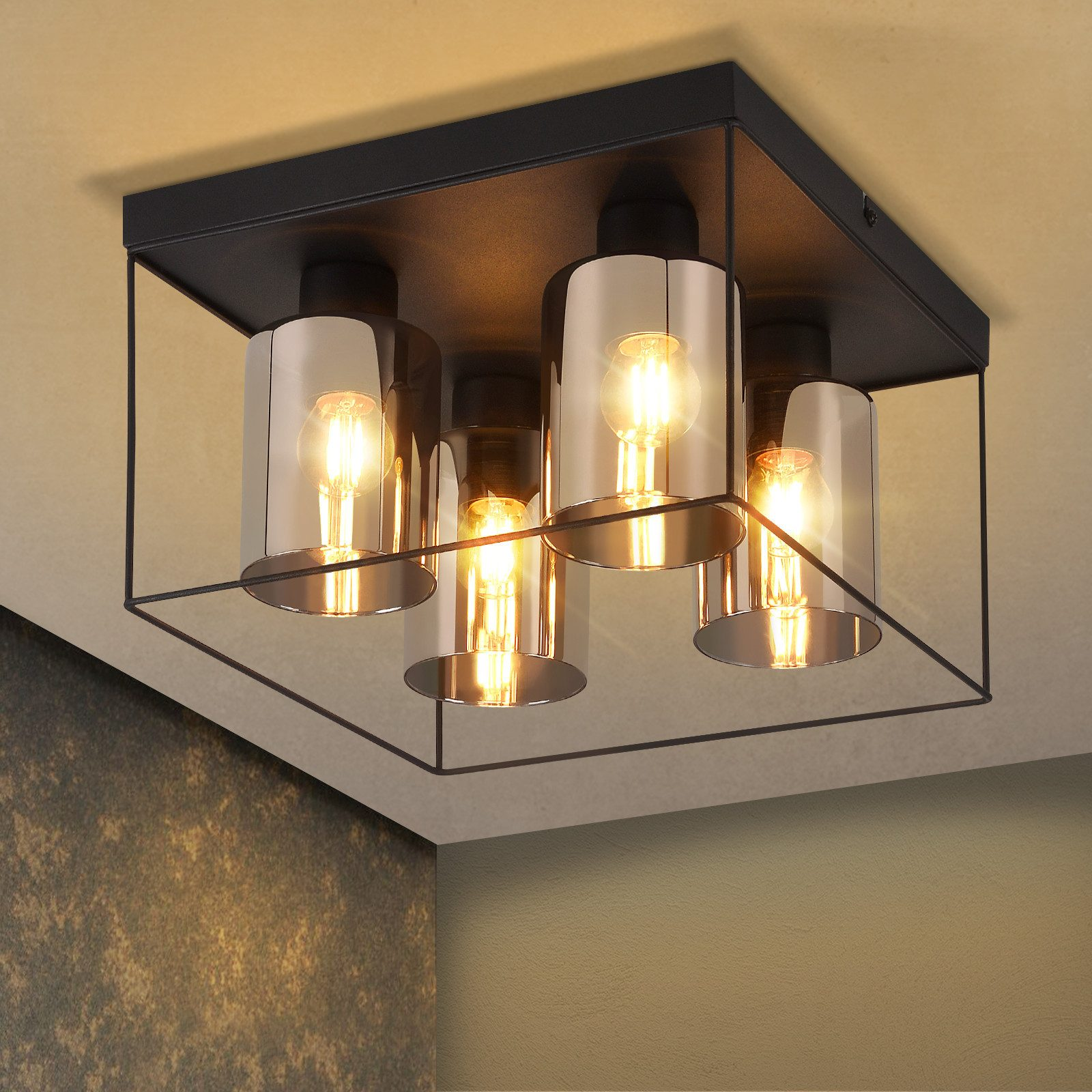 Lampa sufitowa, czarna rama, cztery światła. Neutralne tło, ciepłe światło.