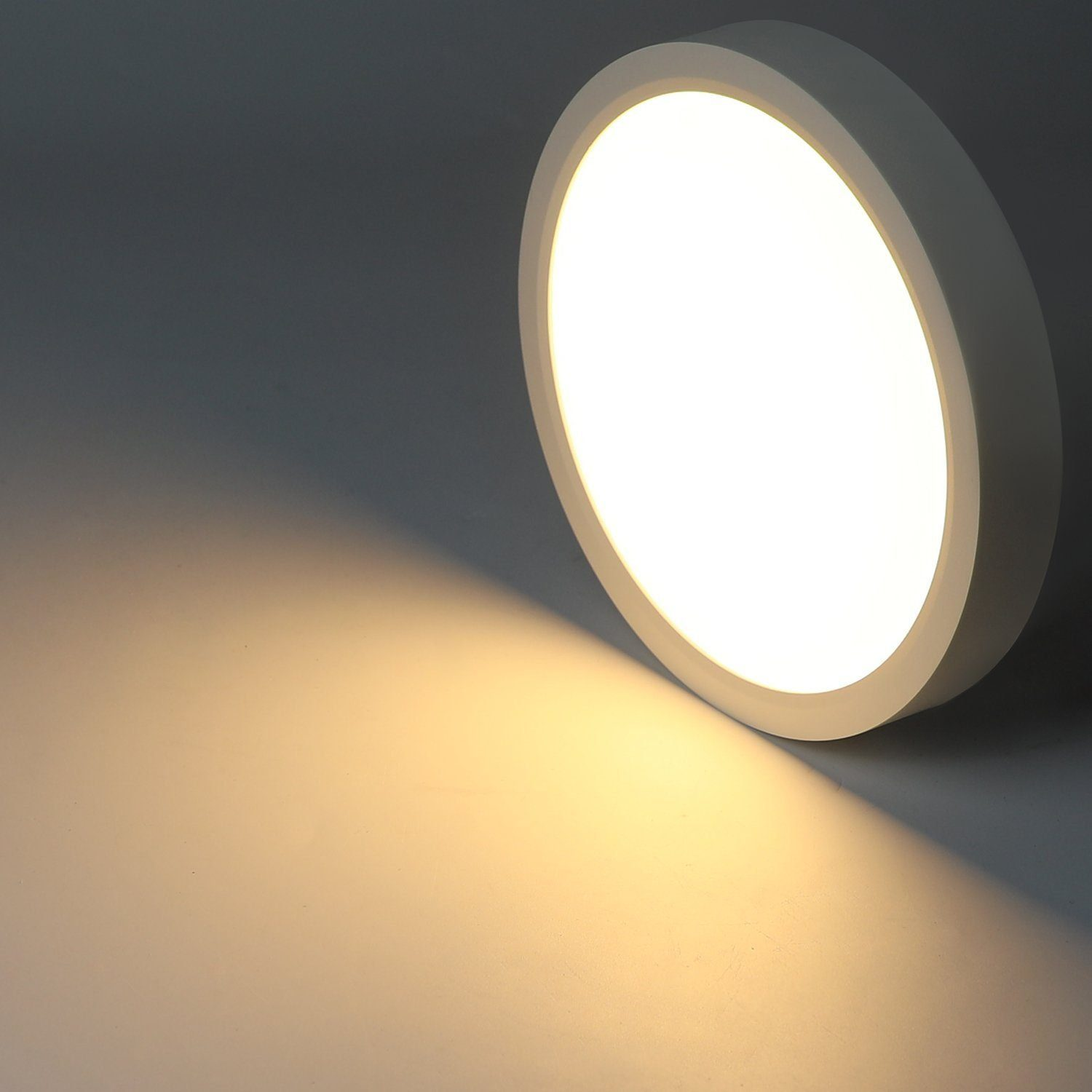 Luz de techo redonda y blanca que emite luz brillante, proyectando una sombra cálida.