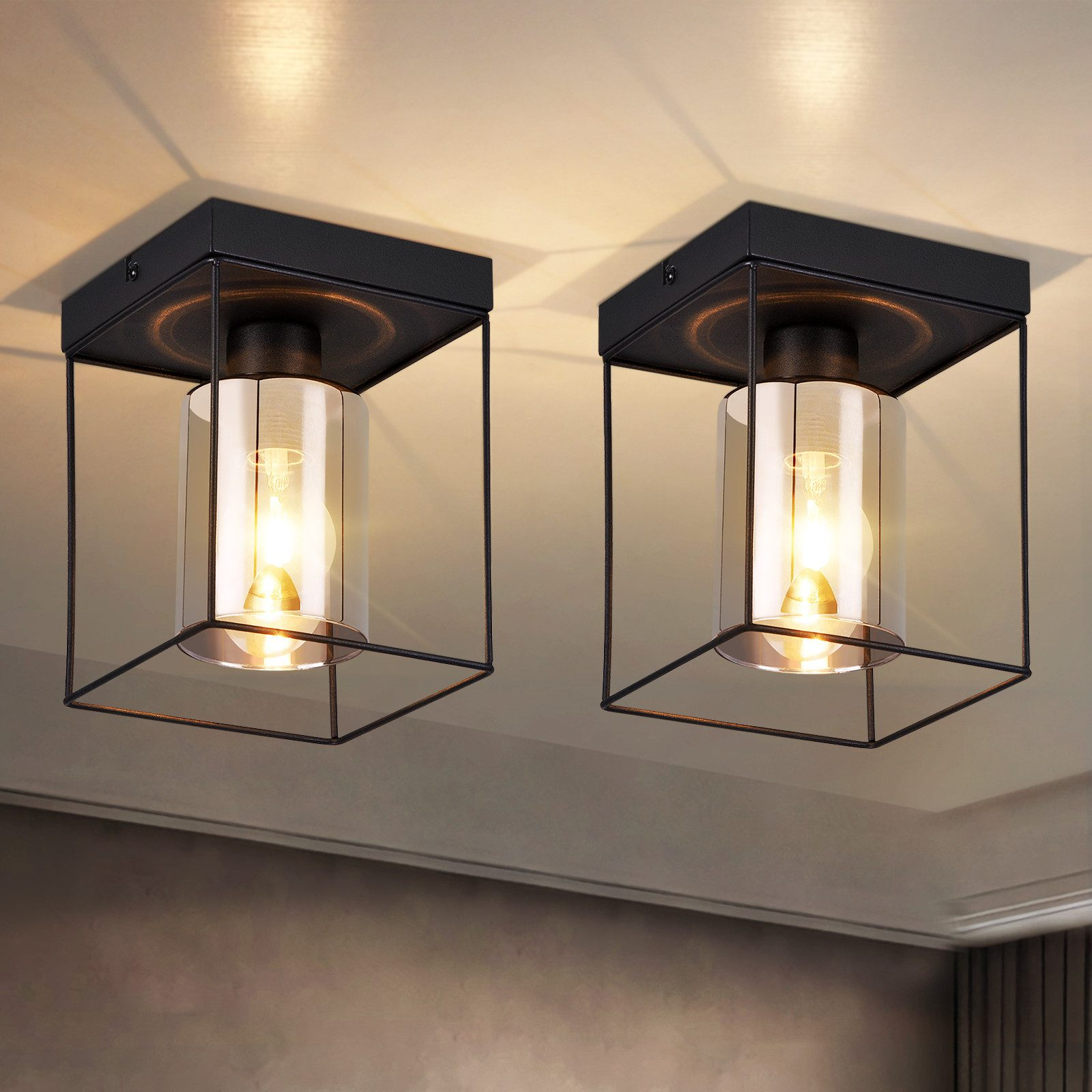 Due plafoniere quadrate nere con cilindri di vetro e una lampadina all'interno.