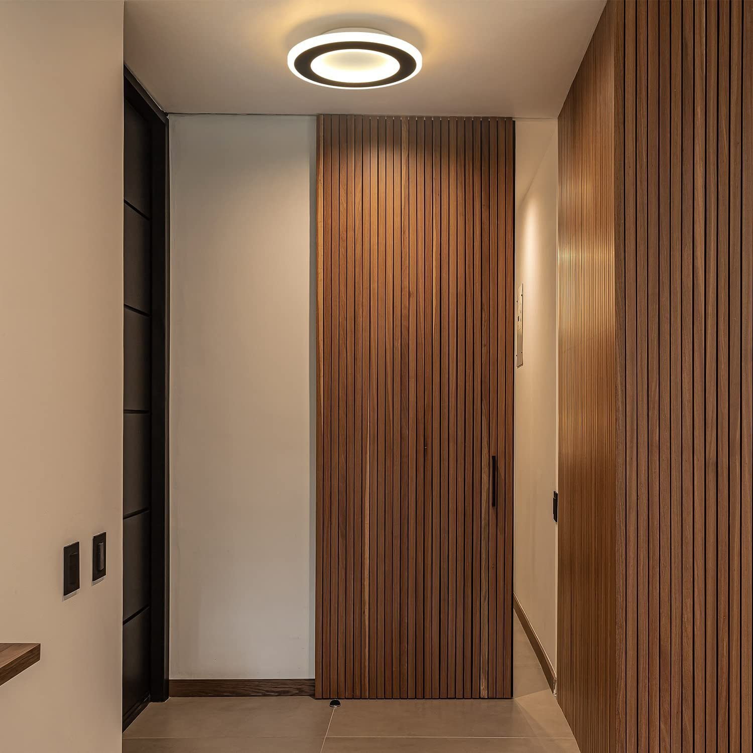Pasillo con paneles de madera, una puerta de madera y una luz de techo circular.