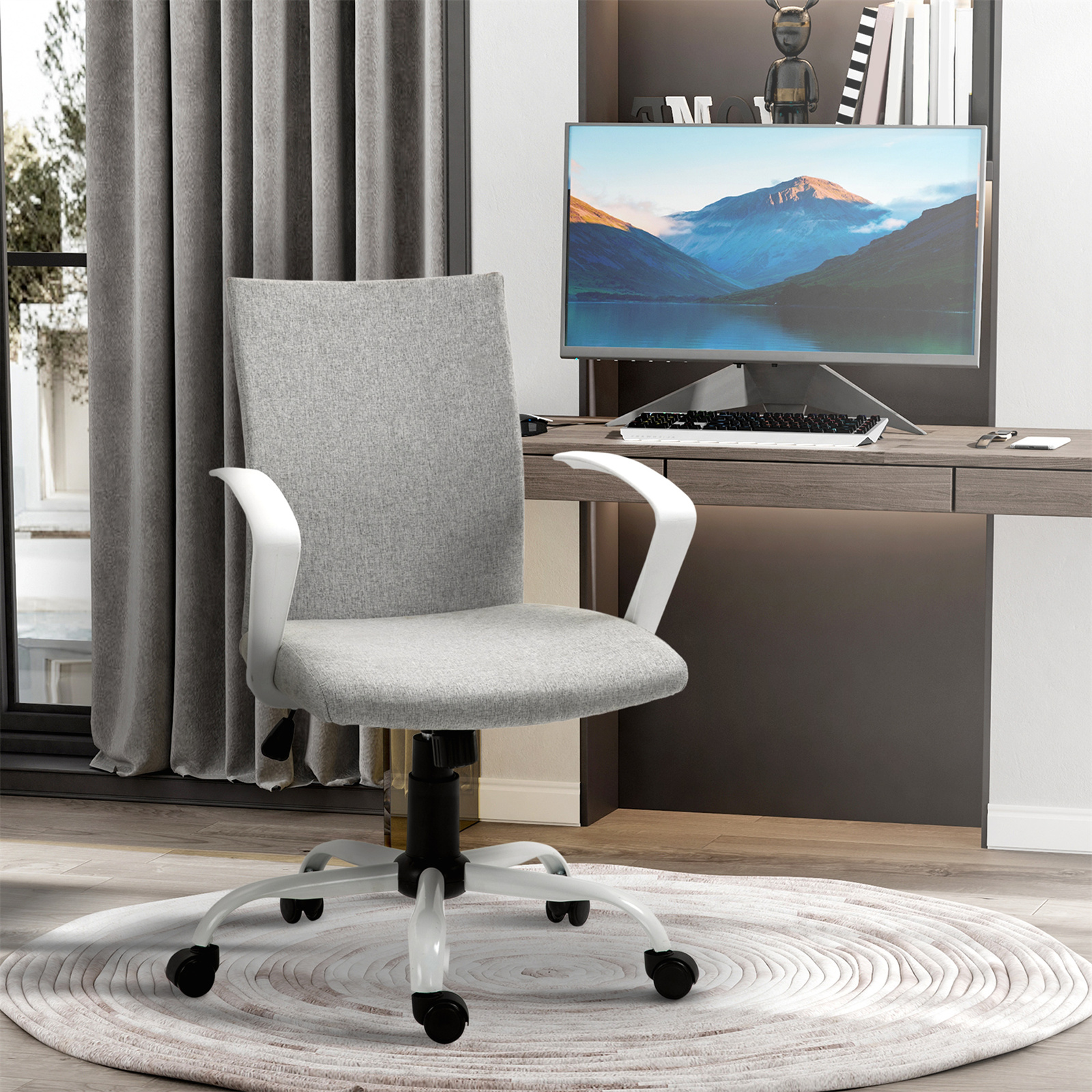 Büro mit grauem Stuhl, Schreibtisch, Computer und Teppich. Fenster links.