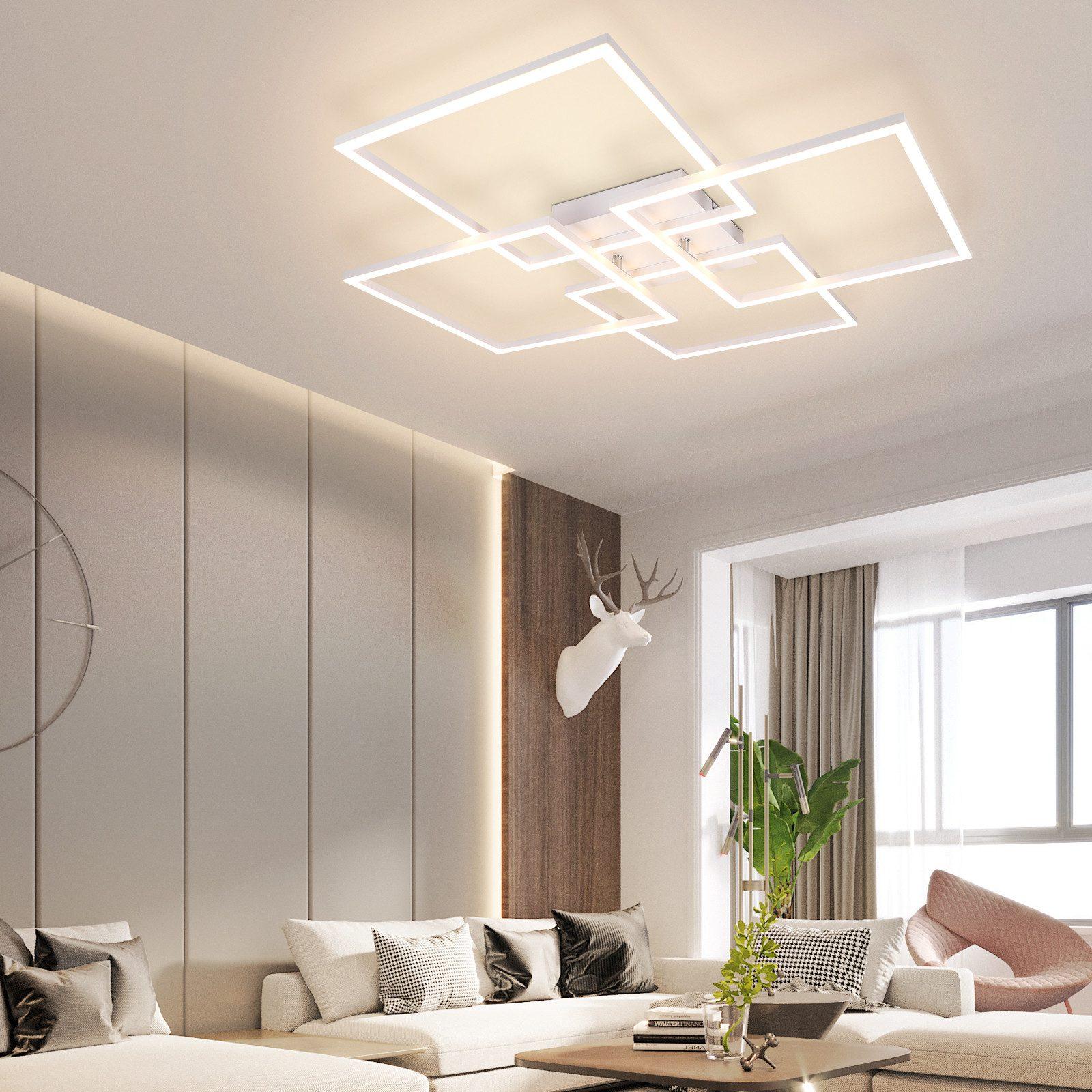 Salon z nowoczesną lampą sufitową i białą sofą. Głowa jelenia na ścianie.