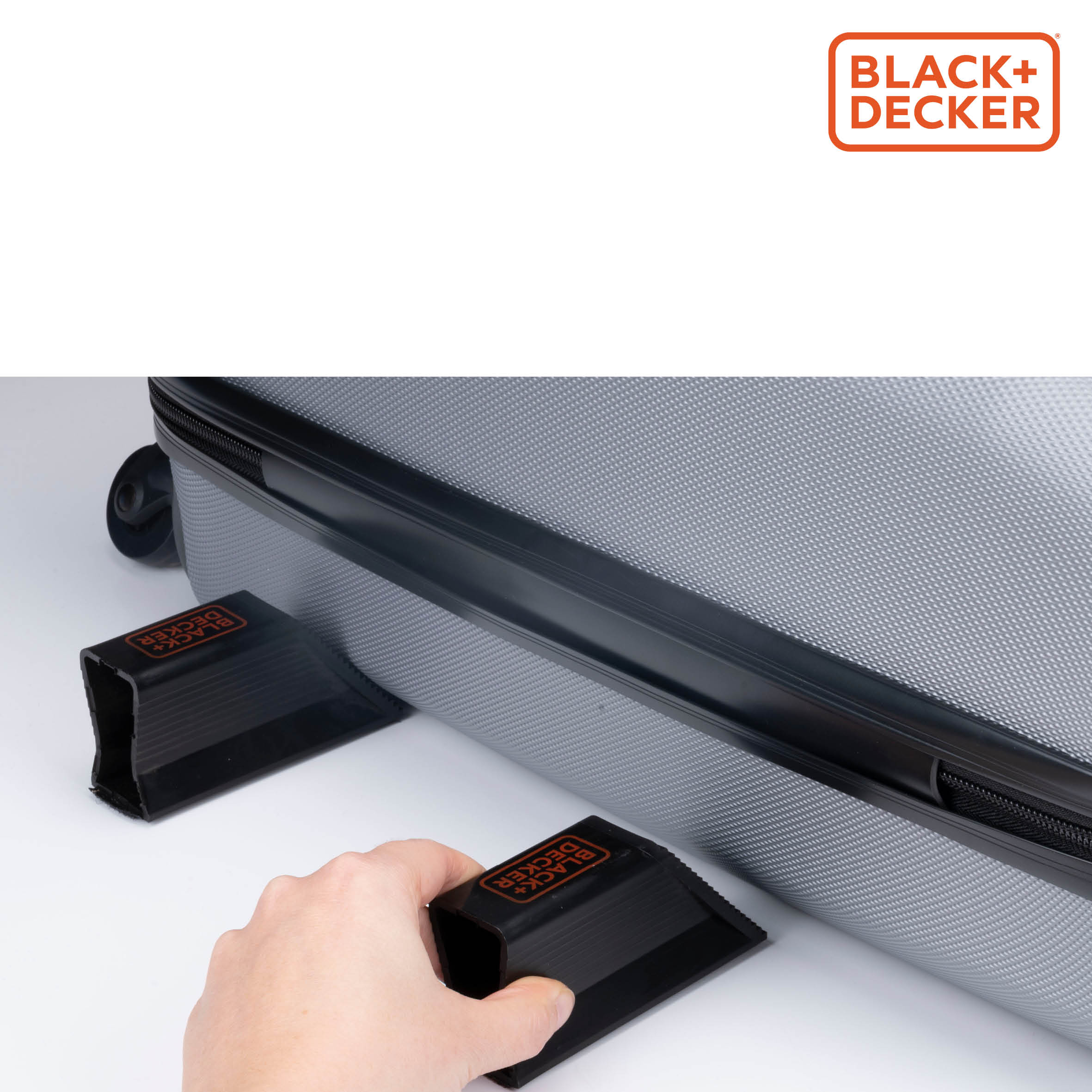 Black+Decker-logo. Een persoon gebruikt gereedschap om een koffer op een wit oppervlak vast te zetten.