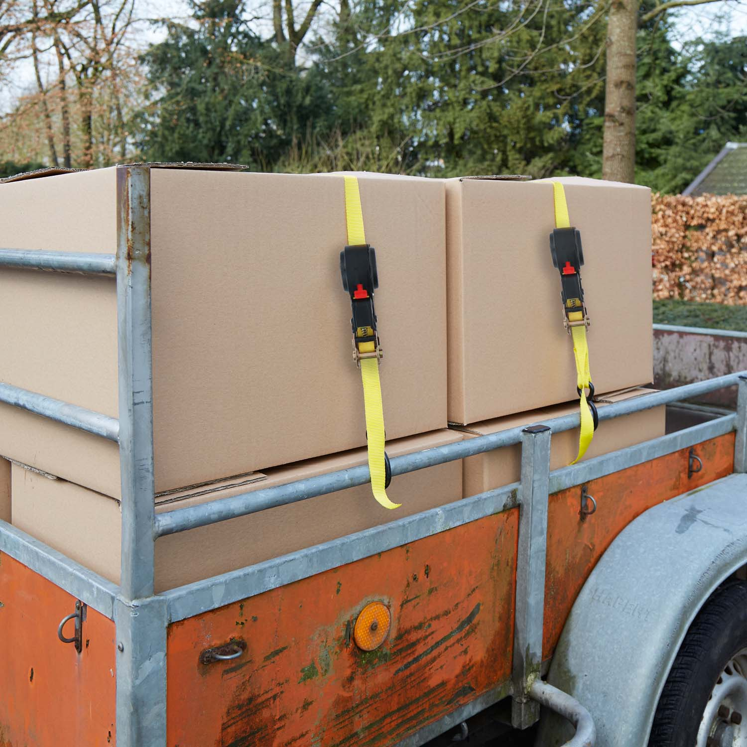 Kisten vastgezet met gele banden op een aanhanger, klaar voor transport.