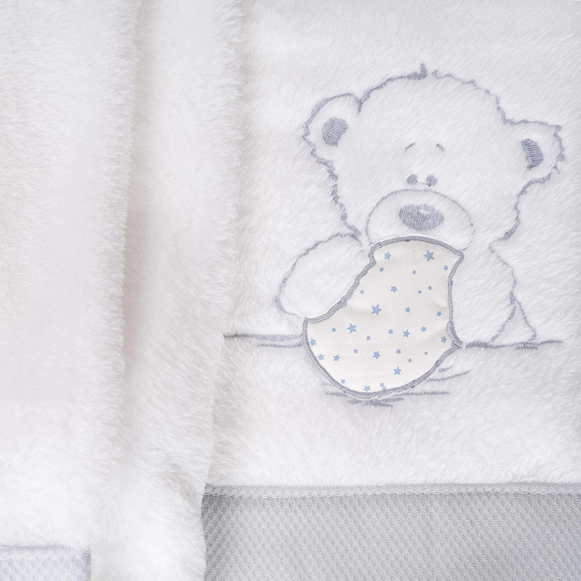 Manta blanca y esponjosa con diseño de oso de peluche y patrón de estrellas azules.