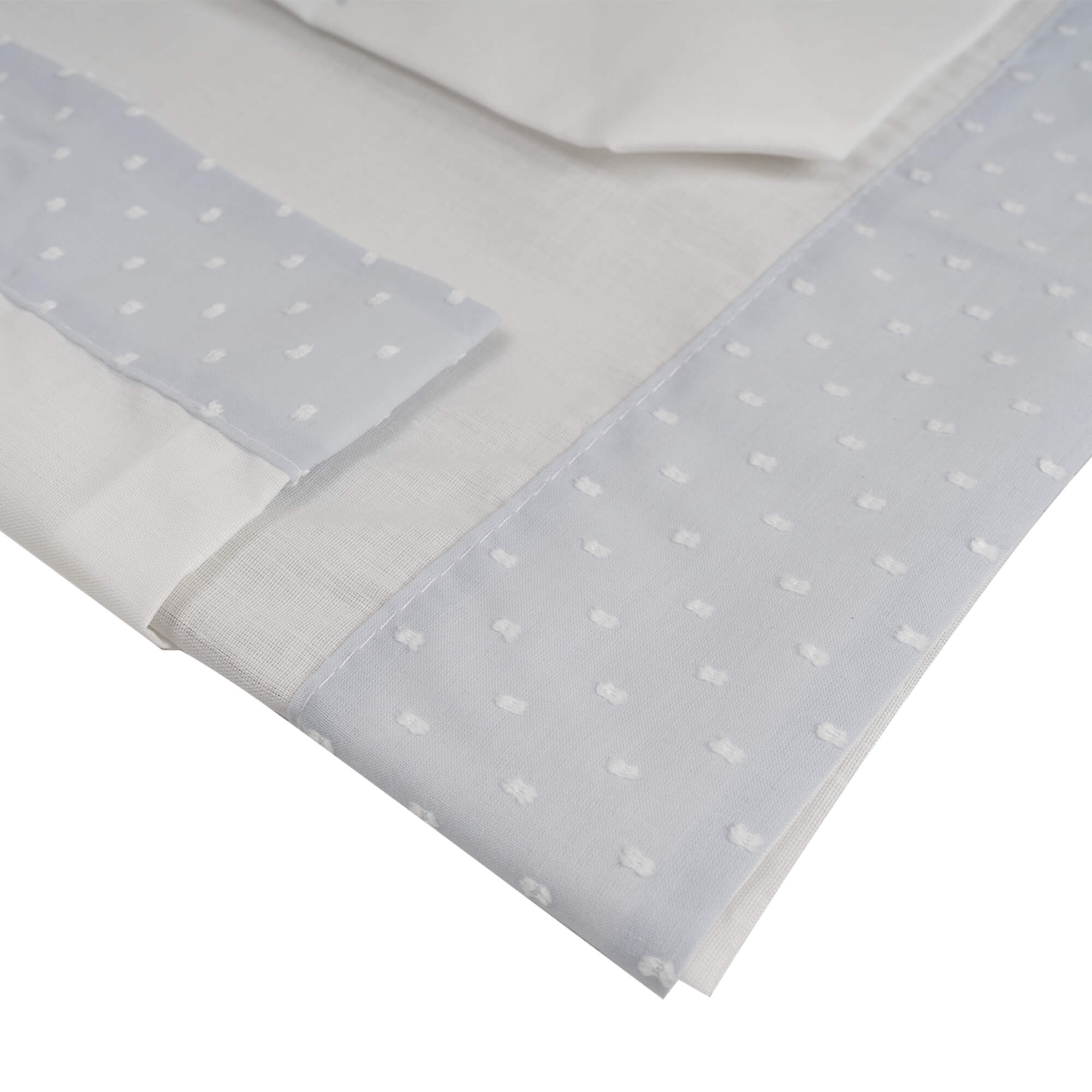 Primer plano de ropa de cama blanca con detalles de puntos azules.