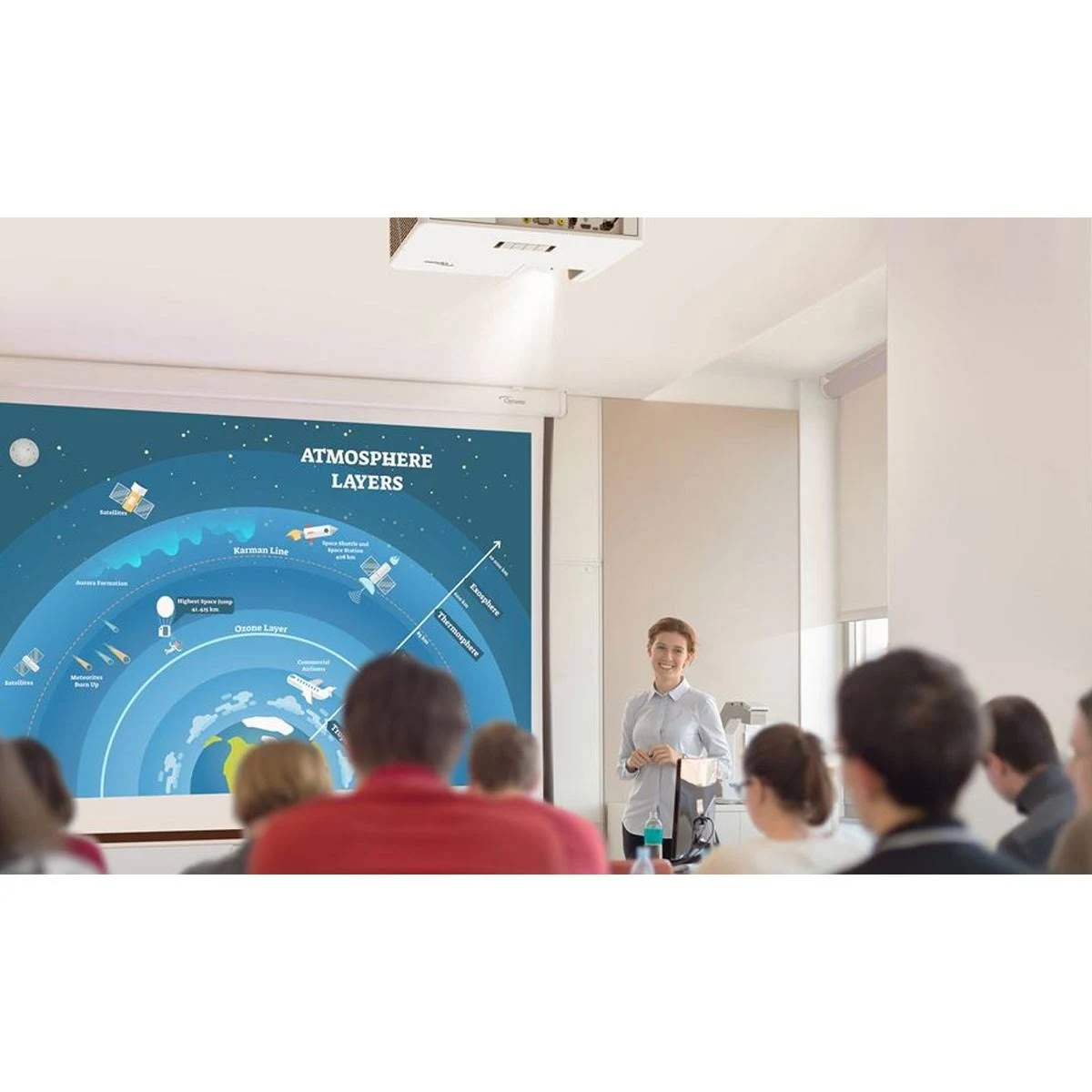 Eine Frau präsentiert einer Gruppe. Ein Projektor zeigt ein Diagramm über die Atmosphäre.