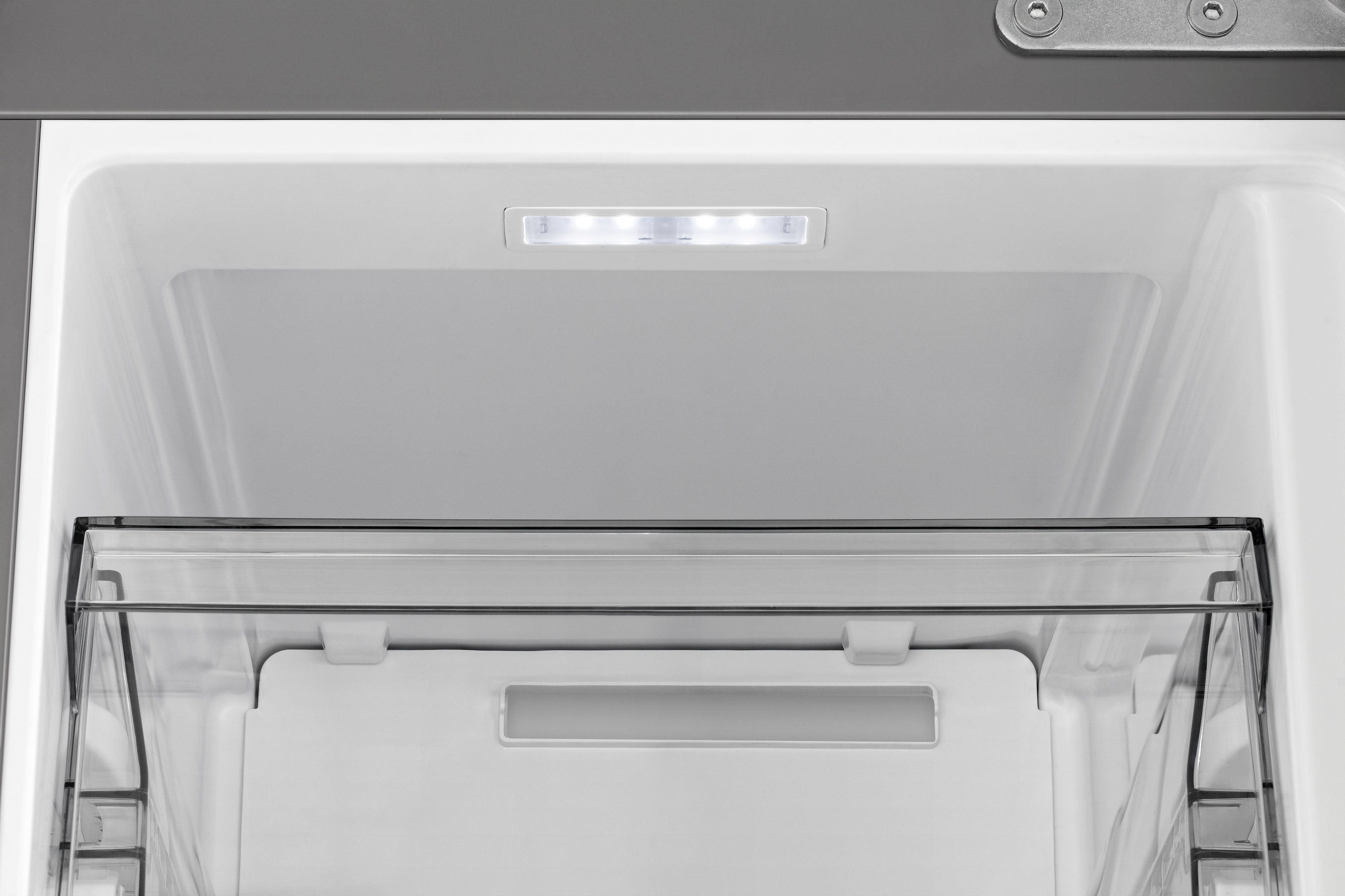 Interno di un frigorifero con una luce, un ripiano e un cassetto trasparente.