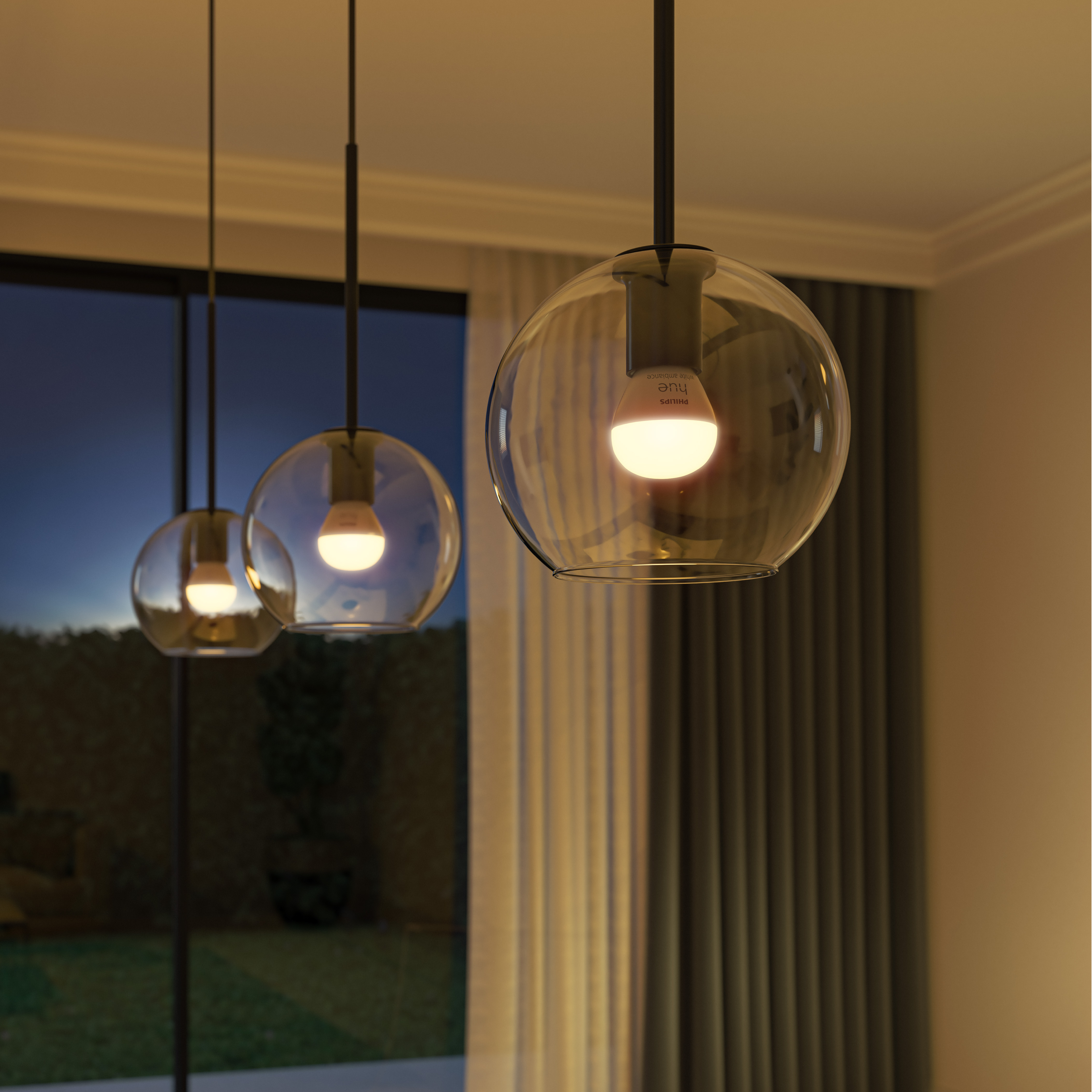 Trzy wiszące lampy kuliste z zapalonymi żarówkami, przed oknem i zasłoną.