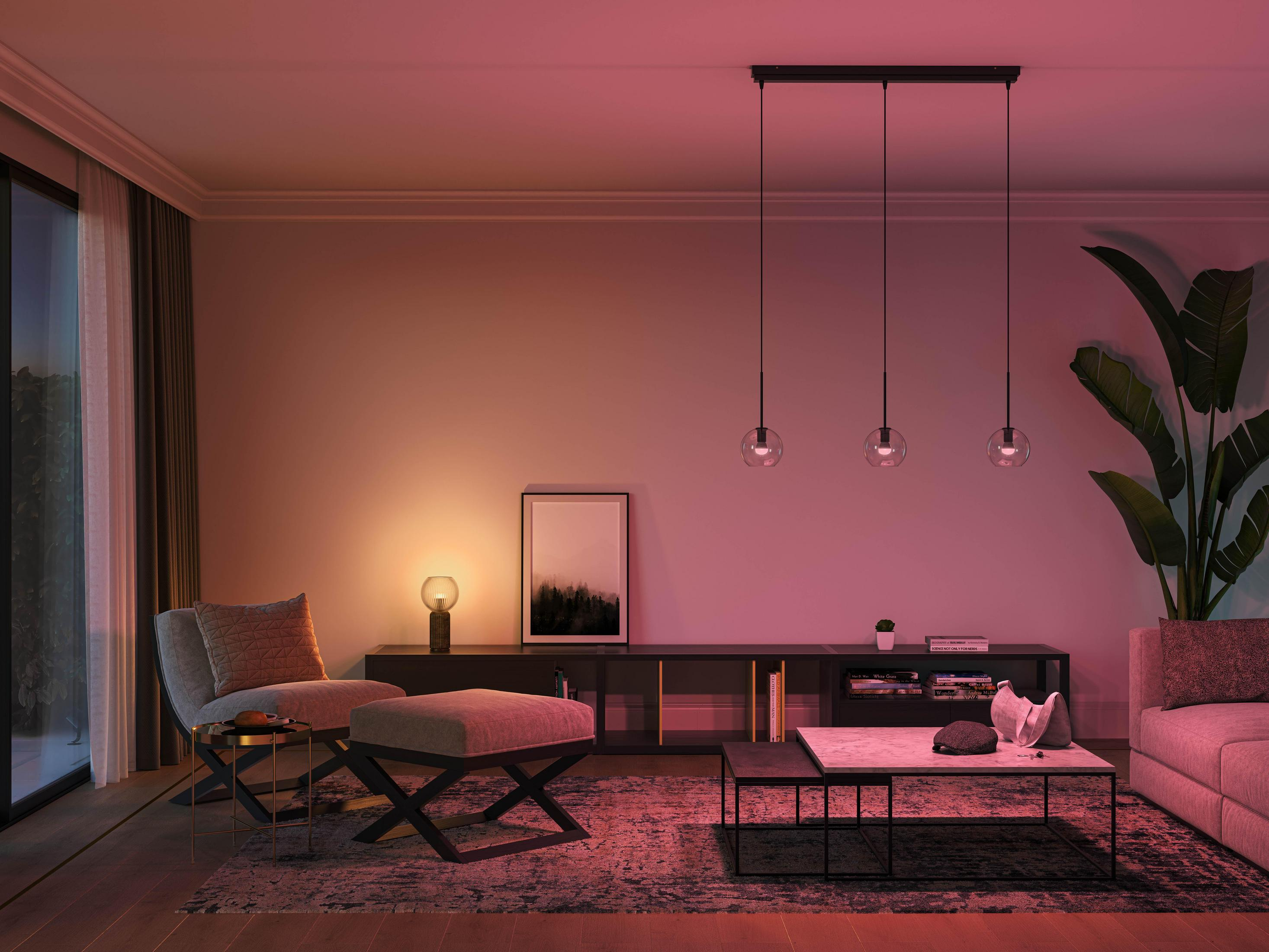 Nowoczesny salon z trzema wiszącymi kulami świetlnymi, sofą i stołem z lampą.