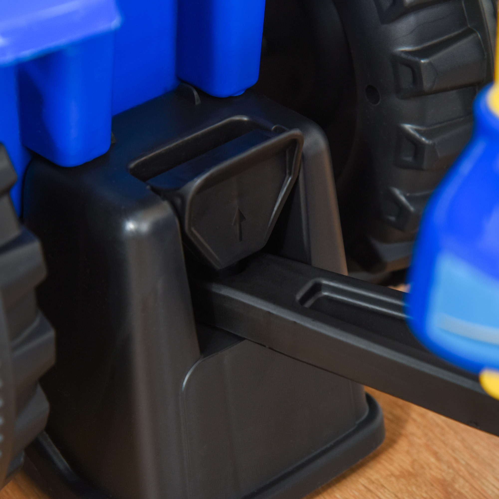 Primo piano di una parte in plastica nera di un veicolo giocattolo blu con una freccia nera.