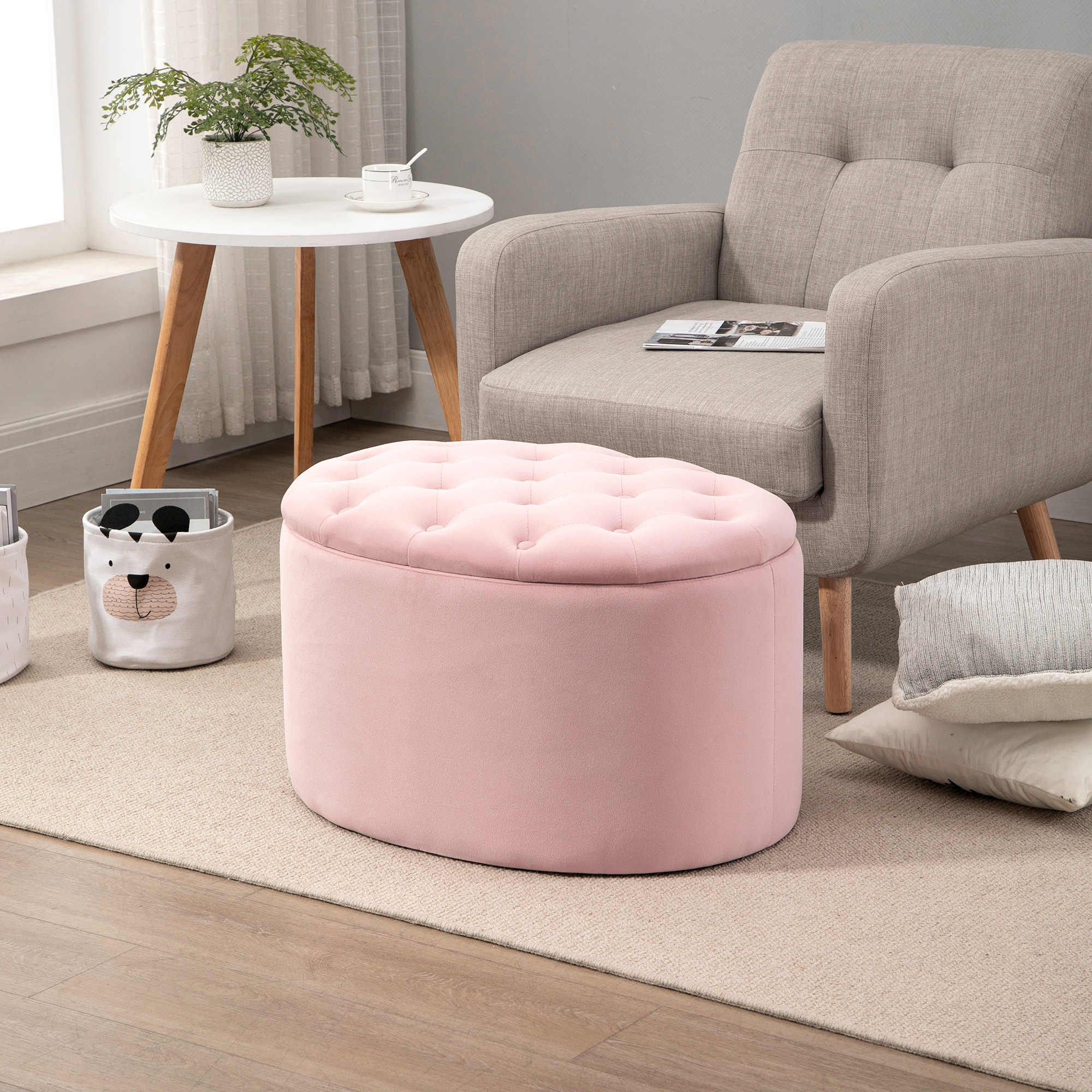 Pouf ovale rosa con trapuntatura a bottoni, posto su un tappeto, vicino a una poltrona grigia.