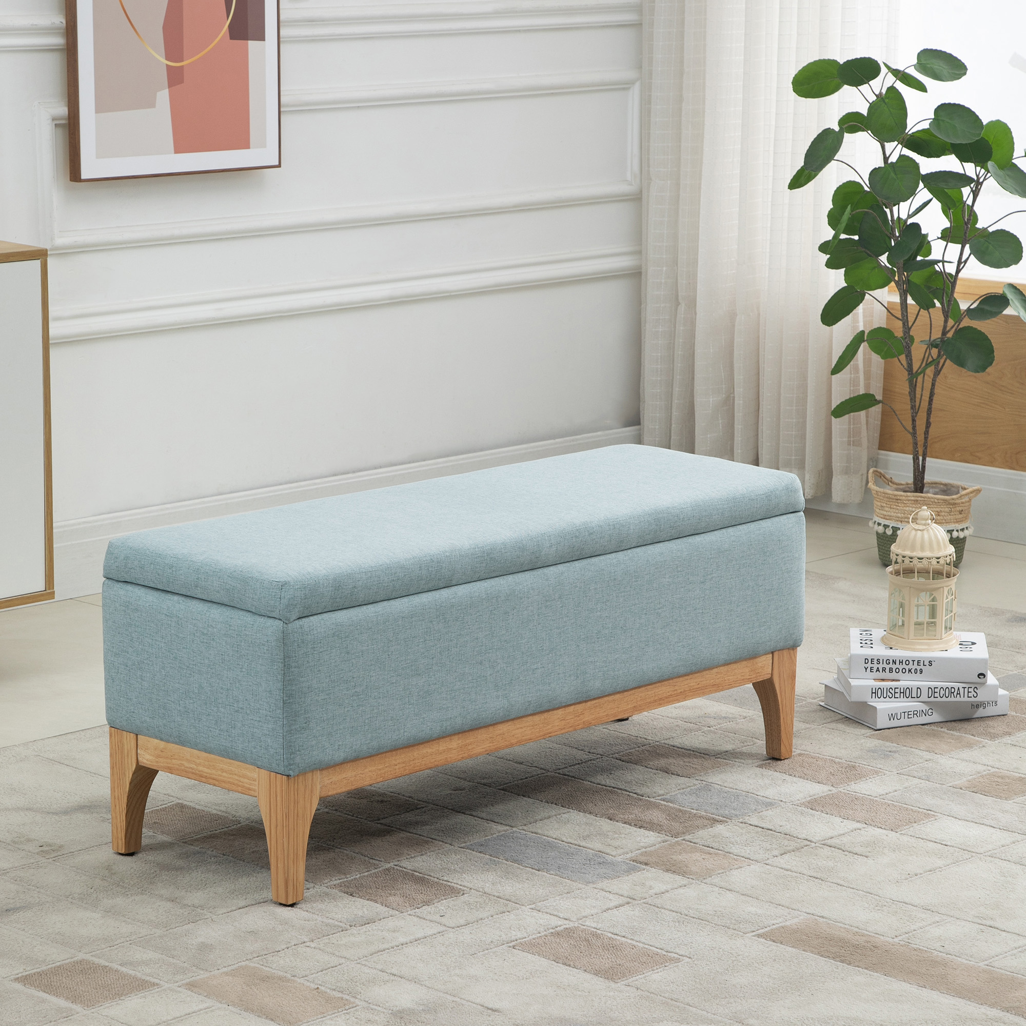 Una panca contenitore blu con gambe in legno in una stanza. Libri sul pavimento.