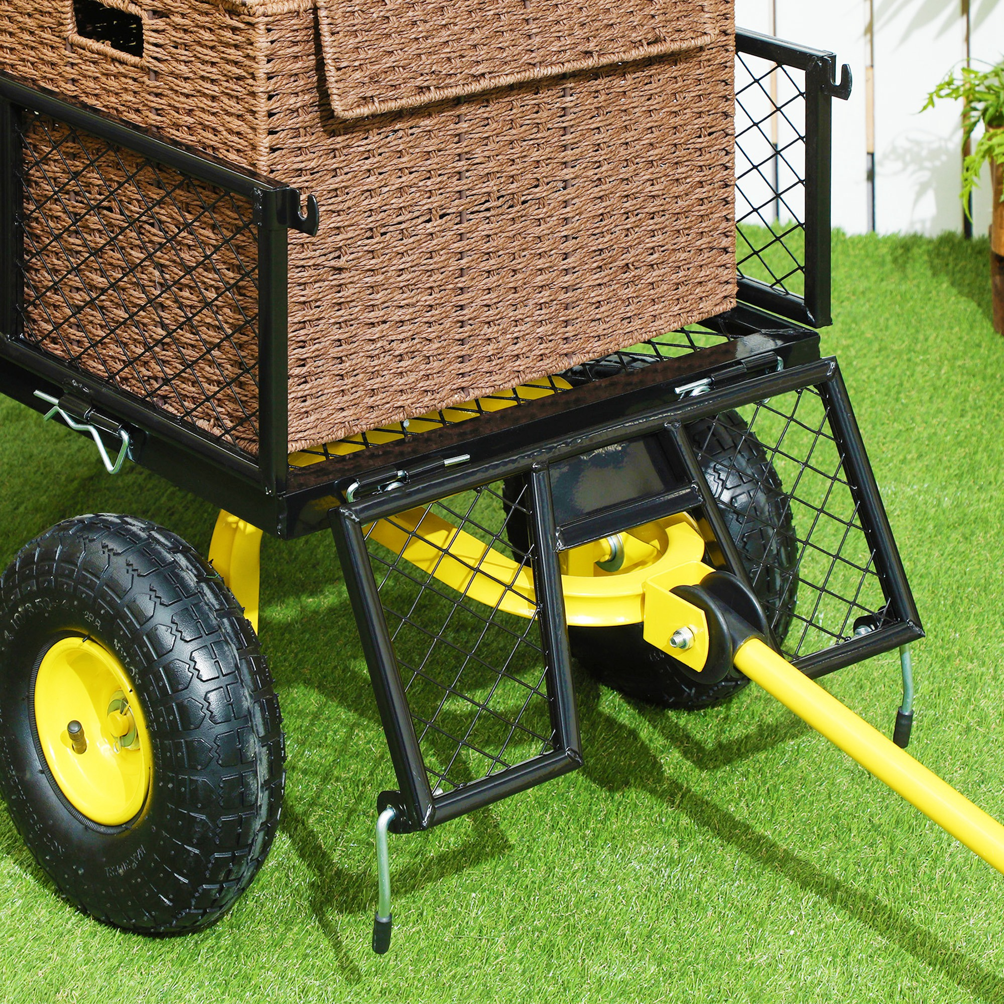 Un carrello nero e giallo su erba verde, con un cesto intrecciato sopra.