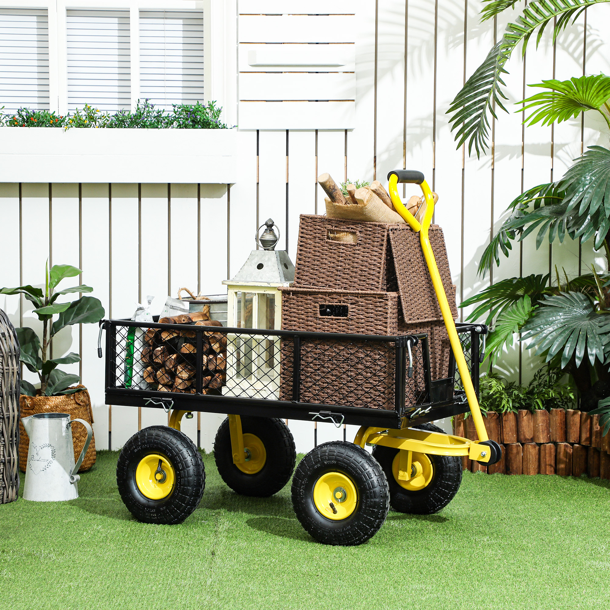 Un carrello da giardino giallo pieno di scatole, tronchi e altri oggetti è sull'erba verde.
