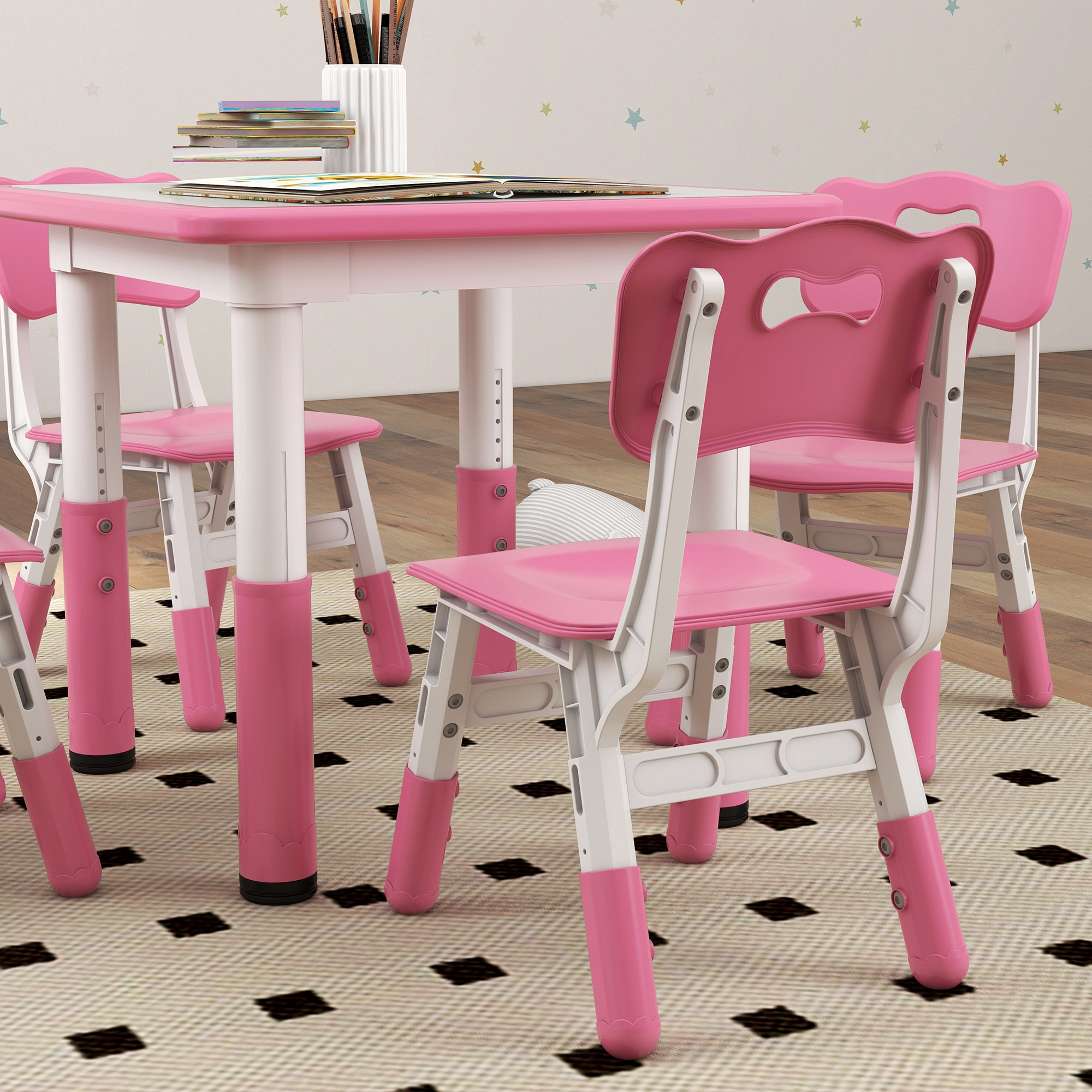 Un tavolo rosa e bianco per bambini con quattro sedie abbinate. Le sedie hanno uno schienale ondulato.