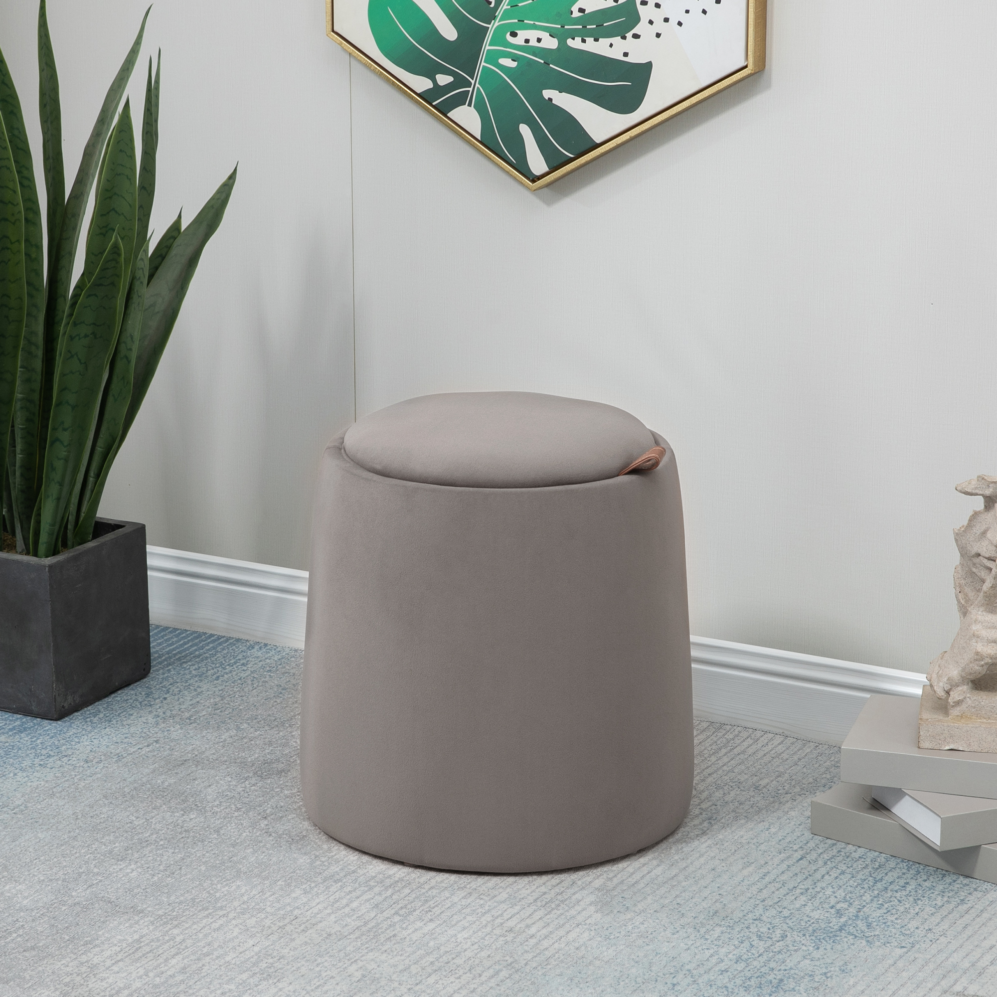 Pouff contenitore grigio con coperchio, posto su un tappeto azzurro chiaro.