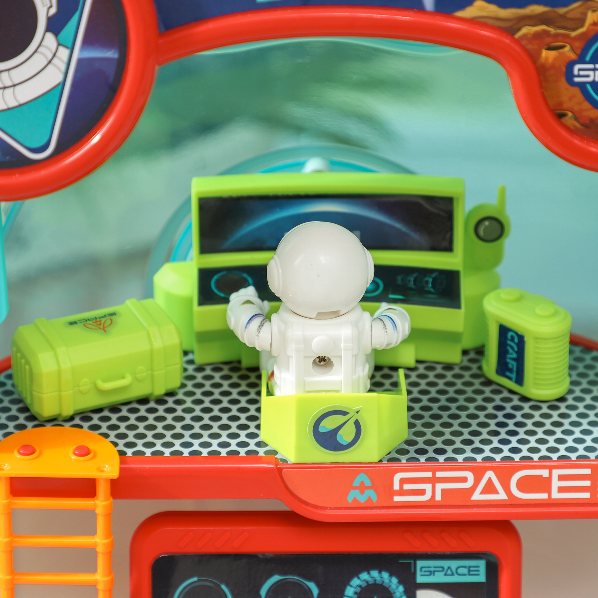 Astronauta giocattolo in un modello di stazione spaziale con elementi verdi e arancioni. L'astronauta è su una sedia.