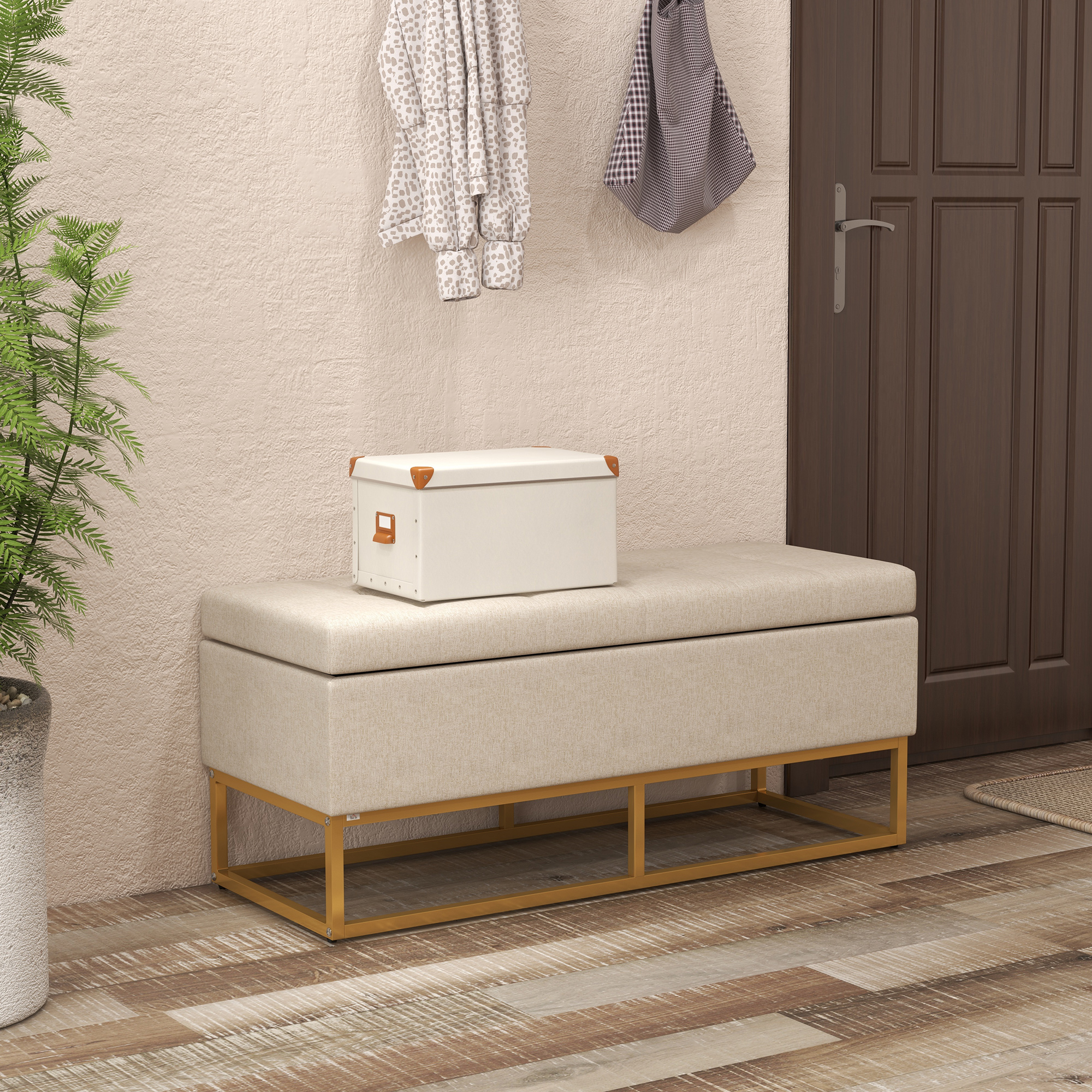 Banco beige con almacenamiento, caja blanca, abrigo y bolso colgando en una pared.