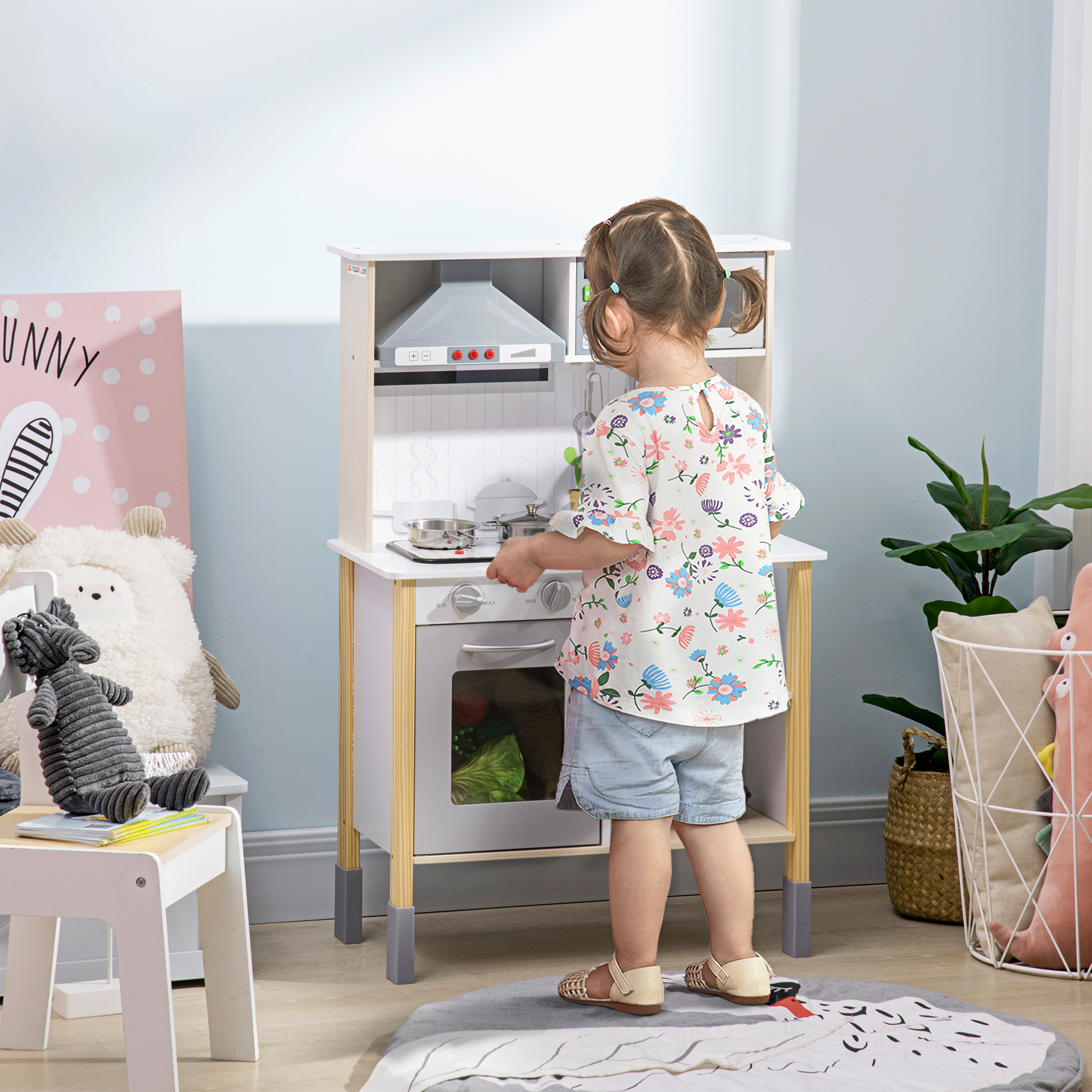 Una bambina gioca con una cucina giocattolo. Un peluche e un tappeto sono anche nell'inquadratura.
