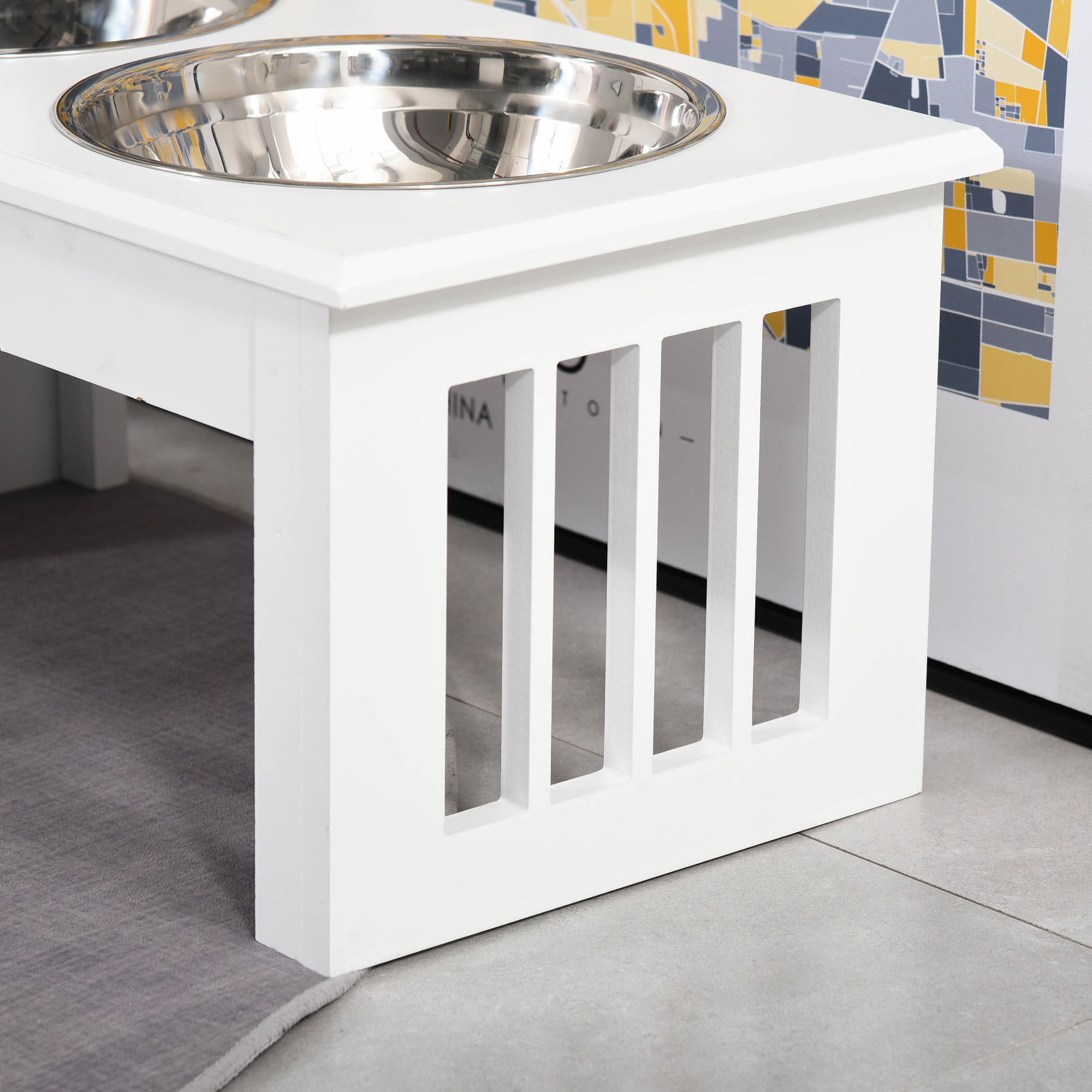 Un primo piano di un supporto bianco per ciotole per cani con un design ritagliato. Ha un tappeto grigio.