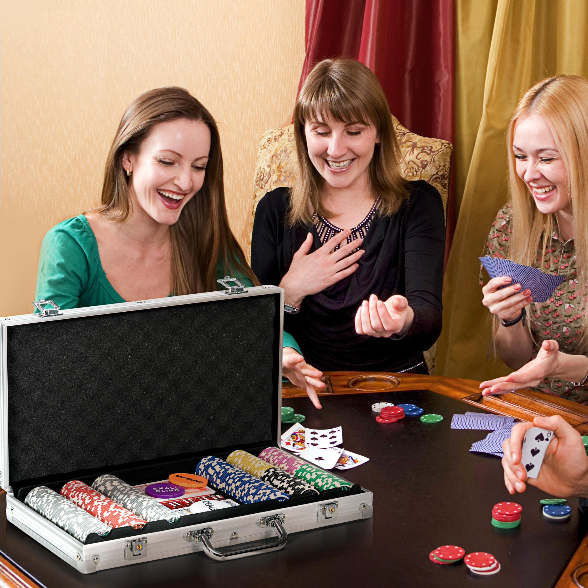 Tre donne sorridono e giocano a poker, con carte e fiches sul tavolo.