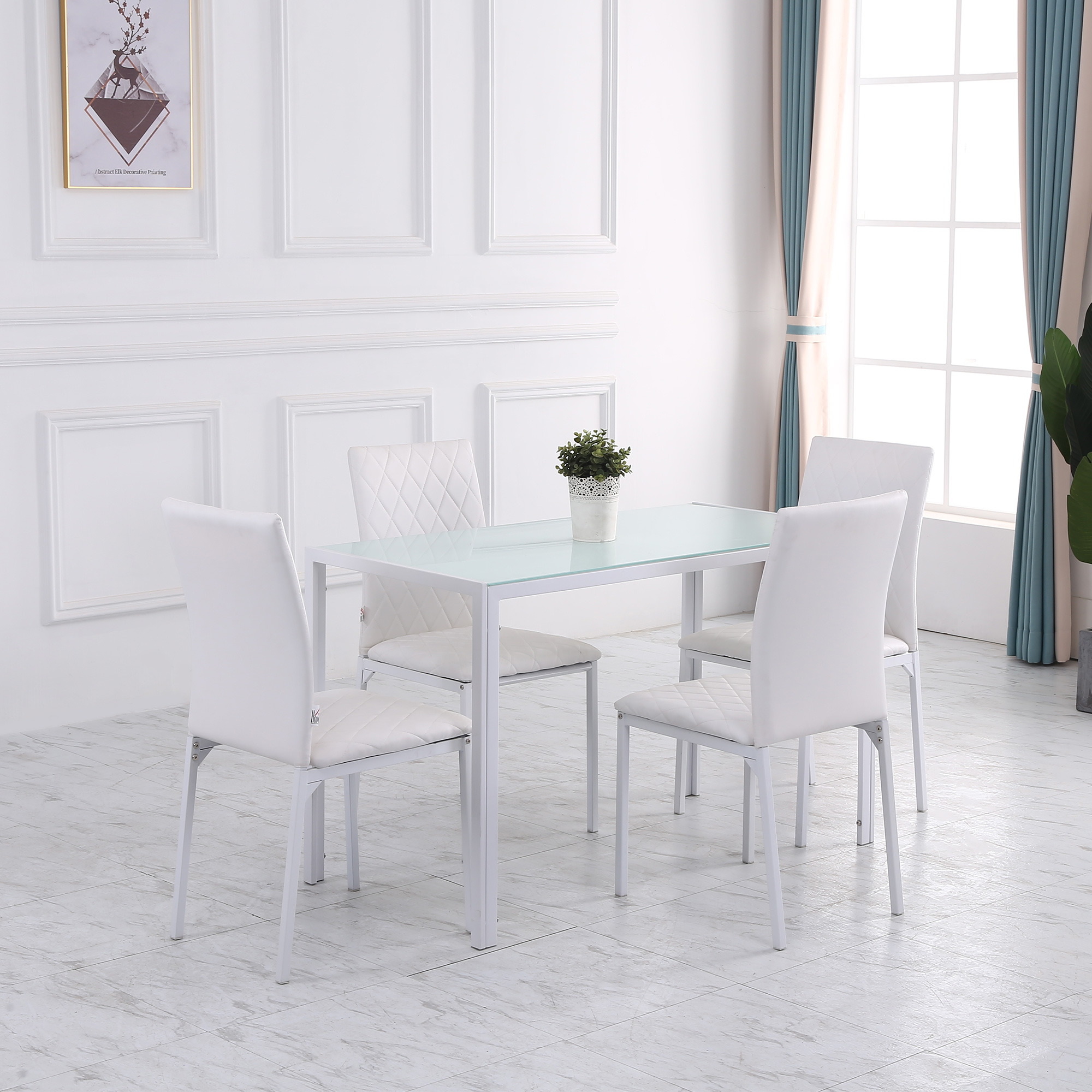 Sala da pranzo bianca con tavolo bianco, quattro sedie bianche e una piccola pianta.