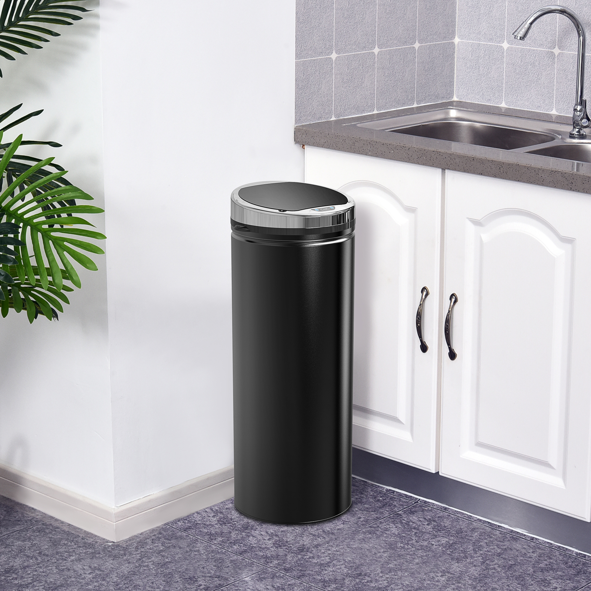 Un cestino nero in una cucina con mobili bianchi e un lavandino.
