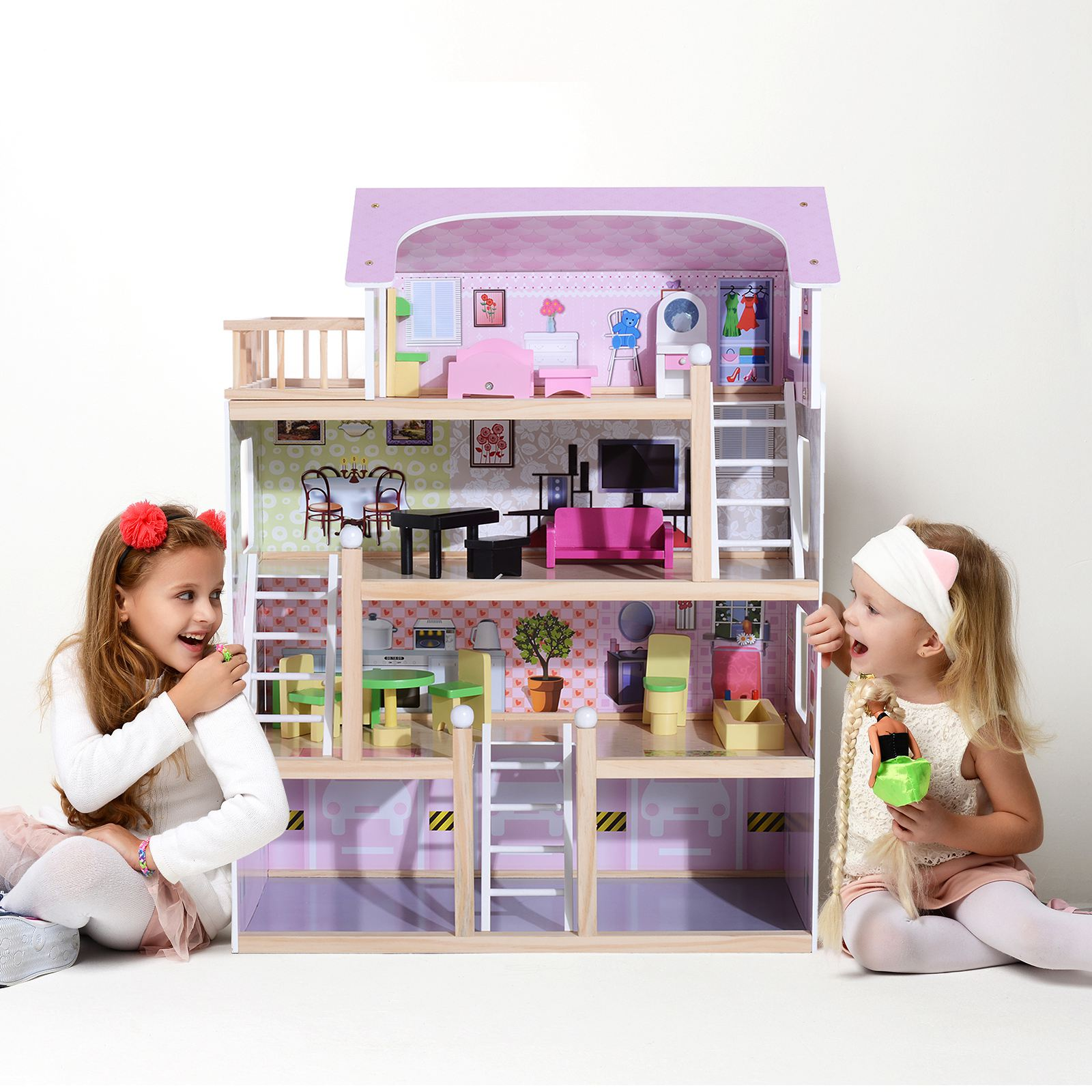 Due ragazze che giocano con una casa delle bambole. La casa è rosa e bianca. Sfondo bianco.