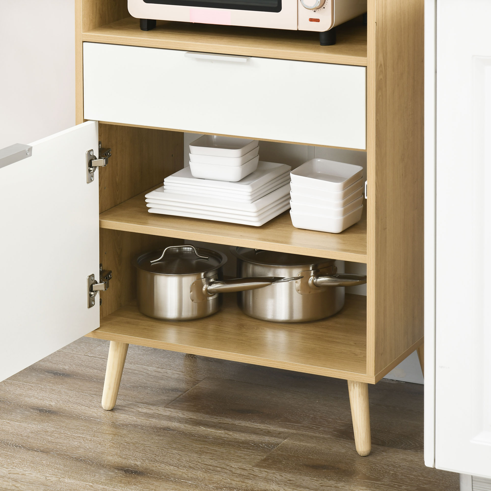 Mobile in legno con anta aperta che mostra piatti e un microonde sopra.