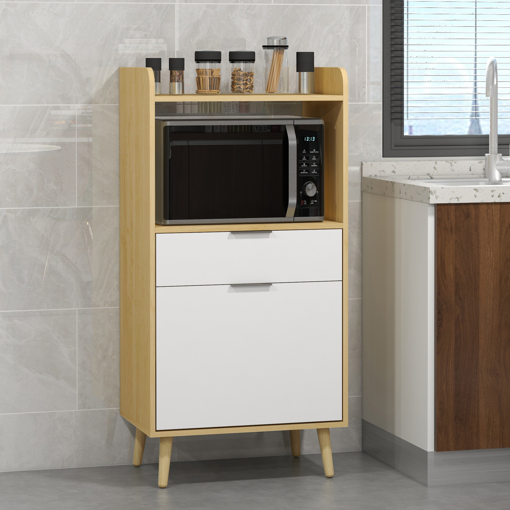 Un mobile da cucina in legno con microonde, cassetti e ripiani con barattoli e spezie. Pulito e moderno.