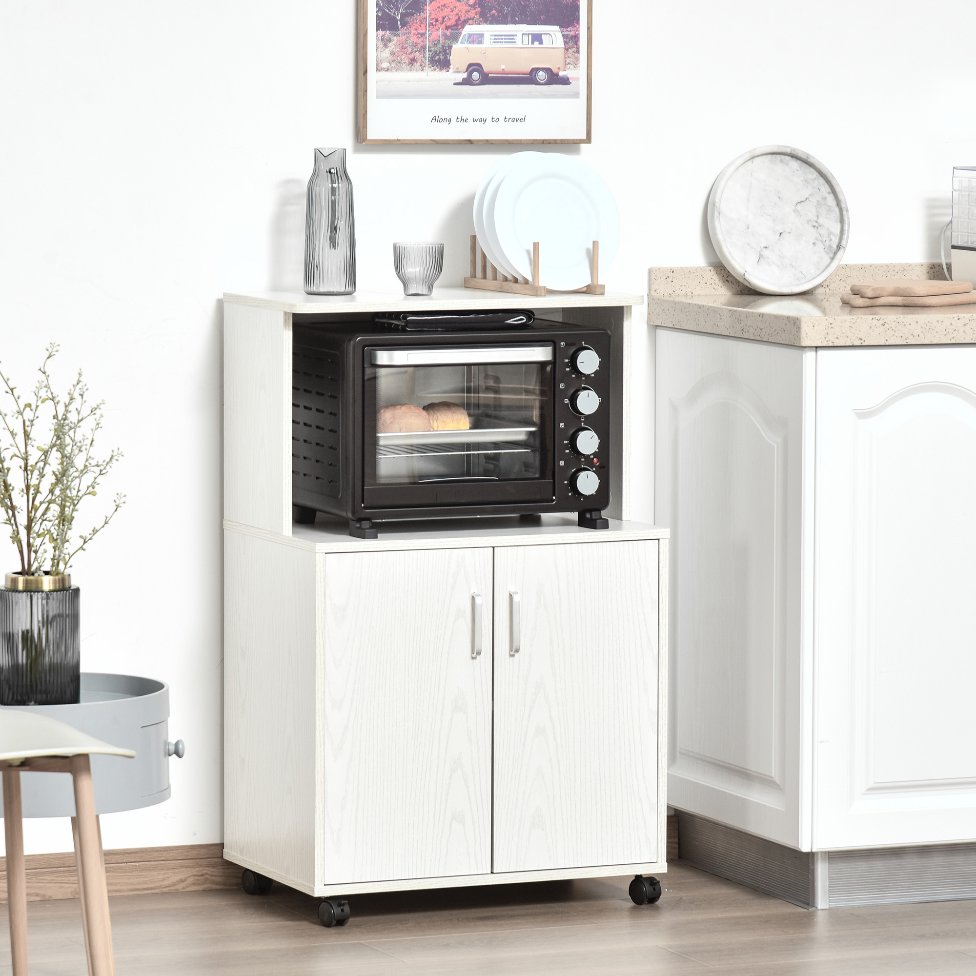 Mobile bianco con forno e ante, barattoli sopra. Vaso con fiori e un dipinto.