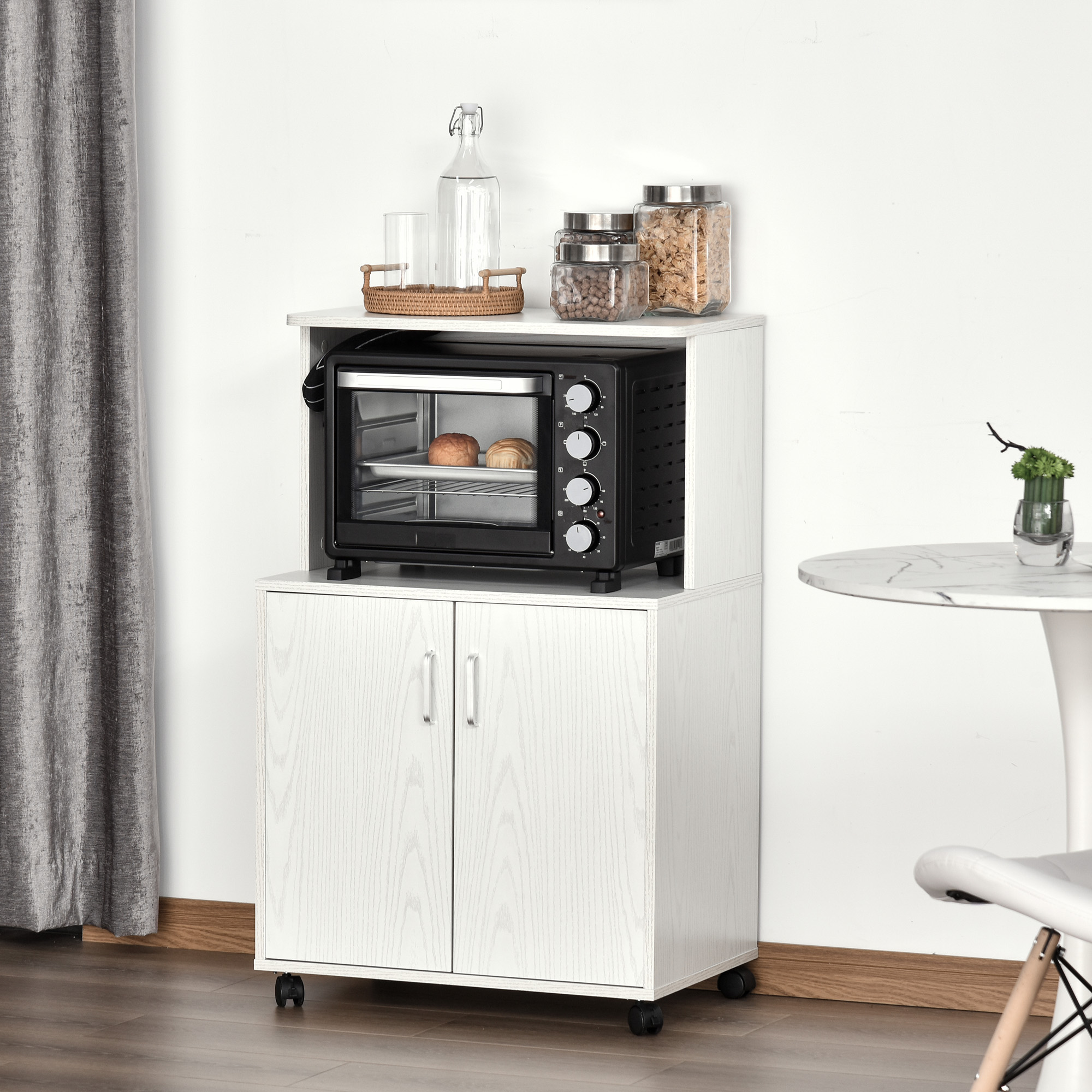 Un mobile con un forno e barattoli sopra, con un tavolo e una sedia bianchi.