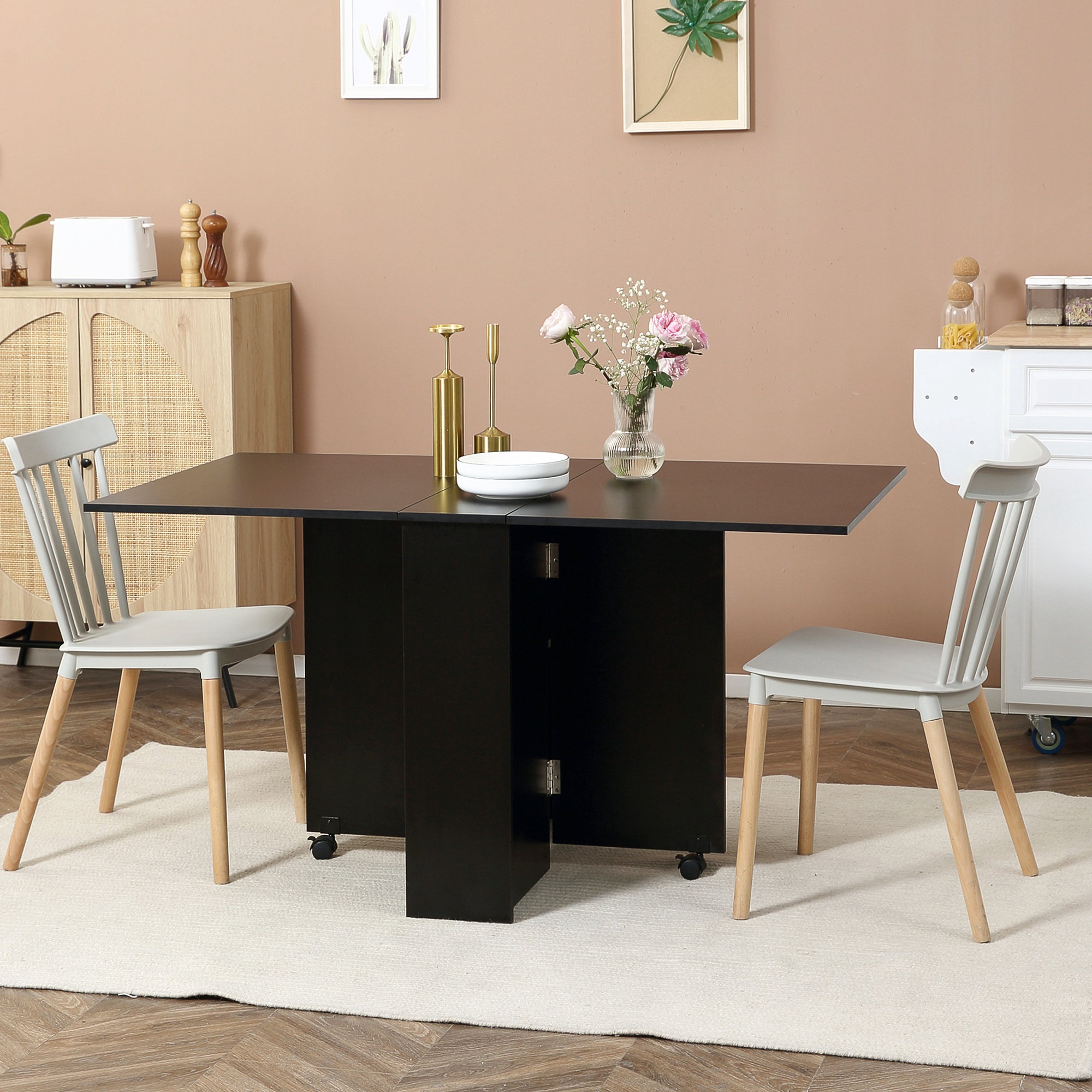 Tavolo da pranzo pieghevole nero con due sedie. Il tavolo ha un tappeto bianco sotto.