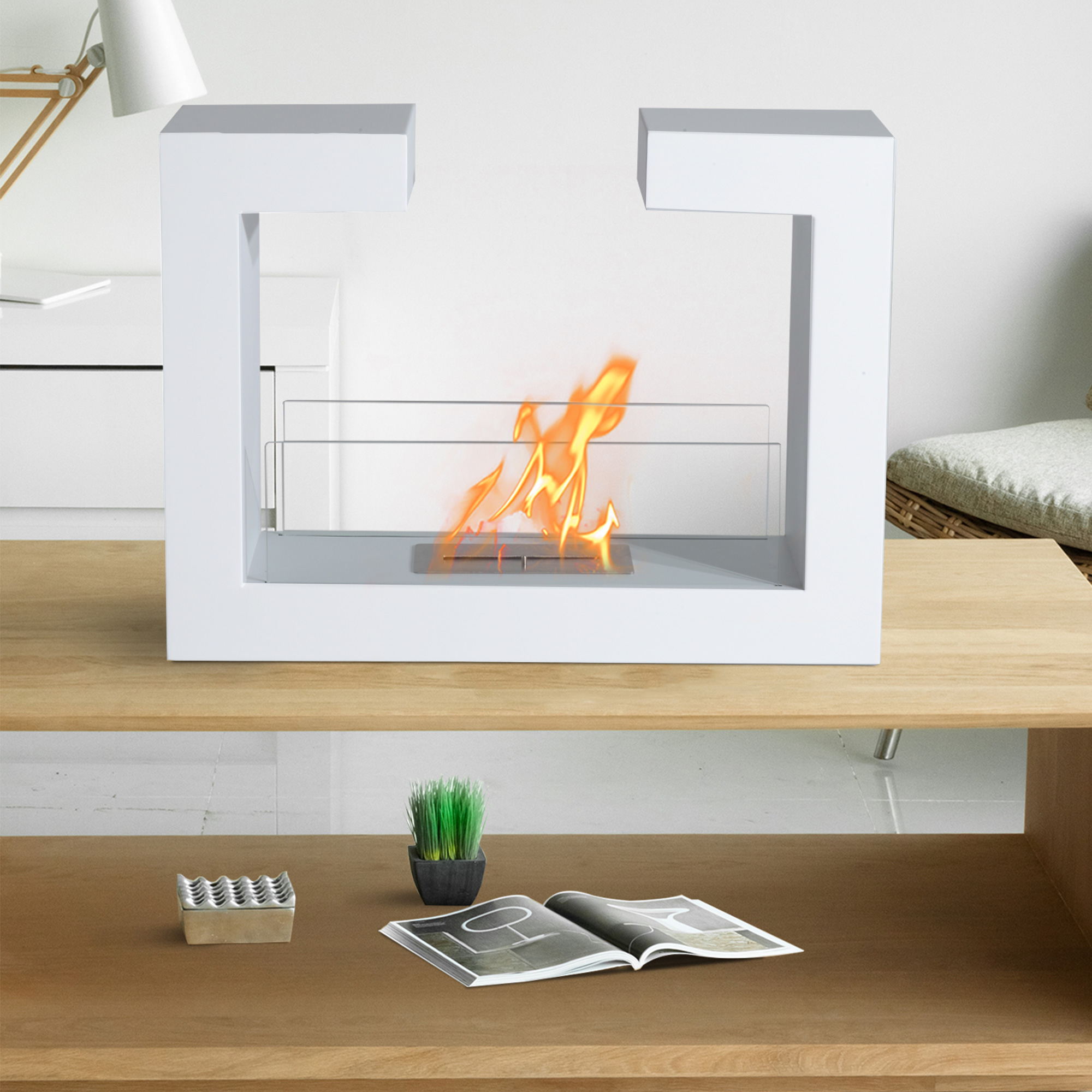 Caminetto bianco con fiamme su un tavolo di legno. Un posacenere e una pianta sono presenti.