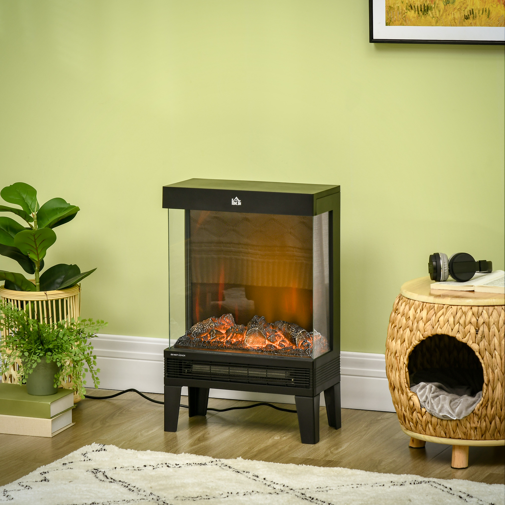 Caminetto elettrico nero con effetto fuoco arancione. Parete verde, piante. Cuccia per gatti in vimini a destra.