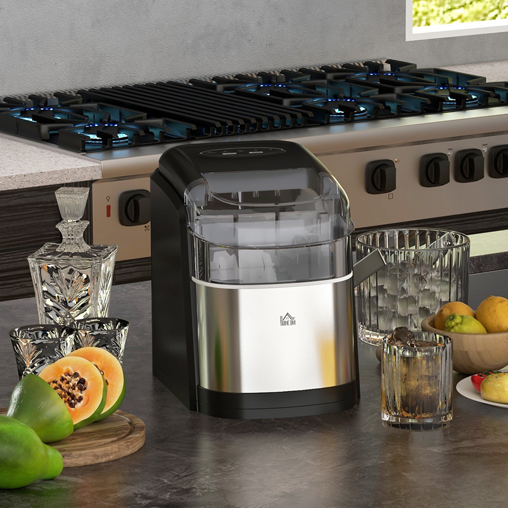 Scena cucina. Macchina del ghiaccio, vetreria, frutta. Piano cottura a gas in acciaio inox sullo sfondo.