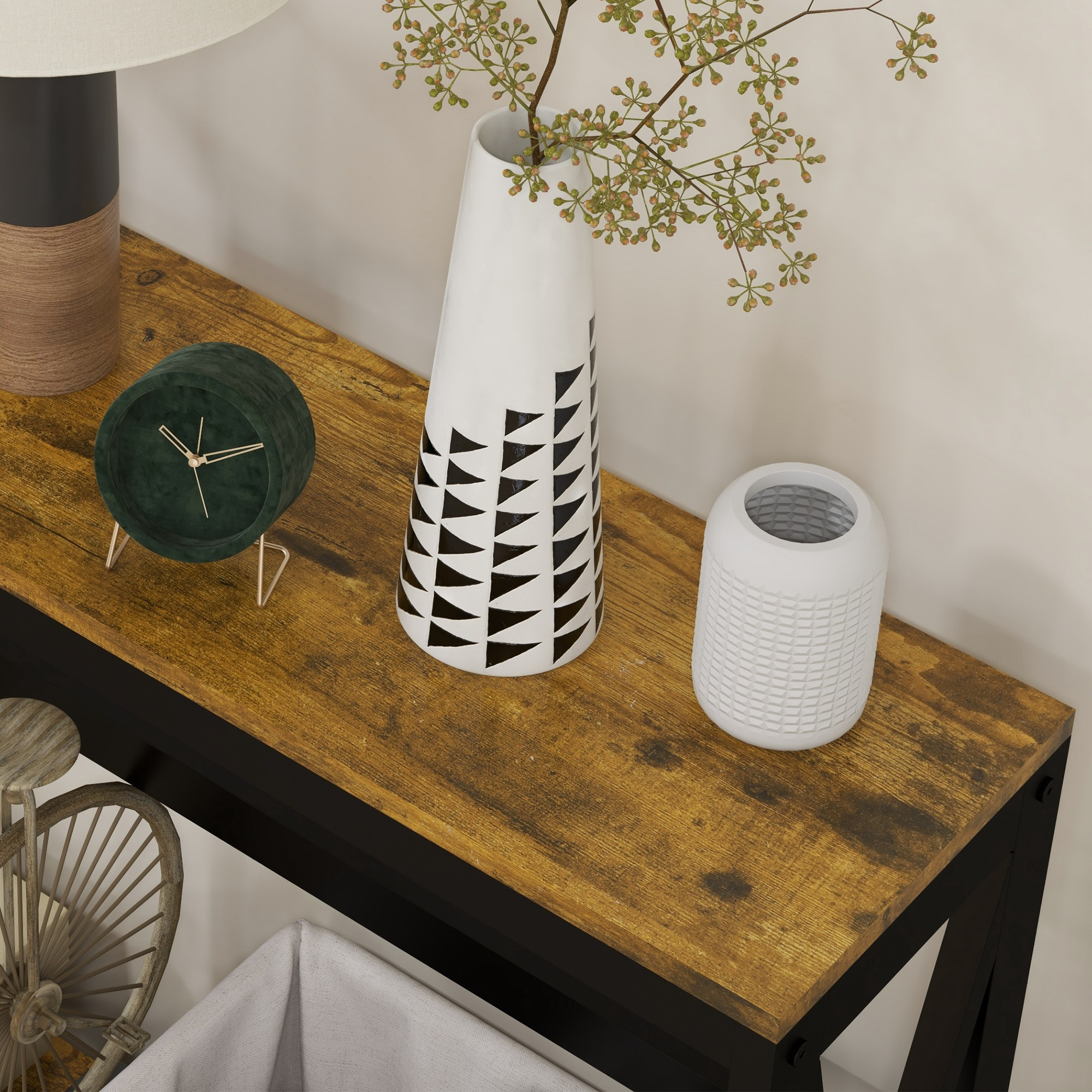 Tavolo consolle in legno con struttura nera e decorazioni. Un vaso bianco con foglie su un piano in legno.