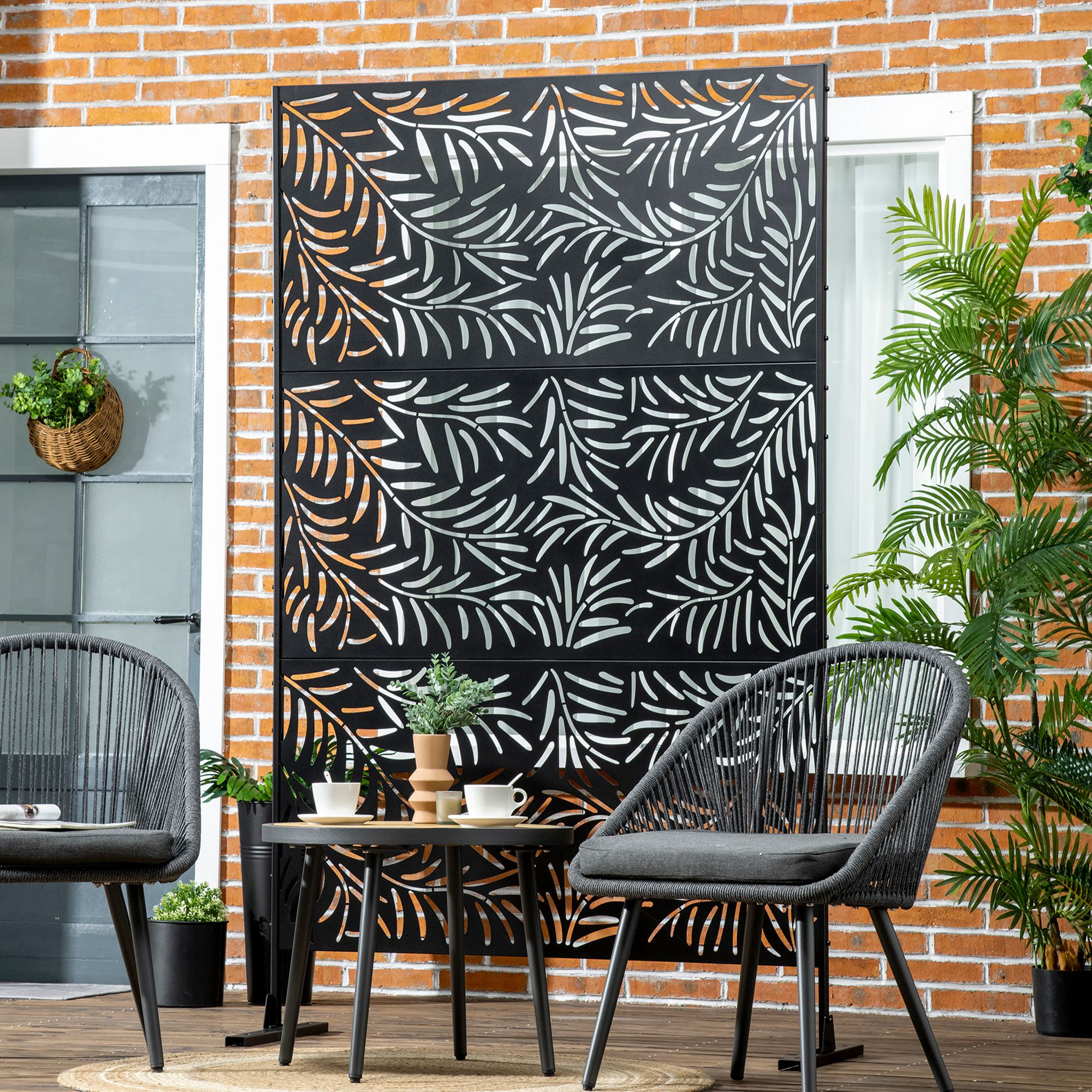 Un patio con uno schermo decorativo nero, tavolo, sedie e piante in vaso.