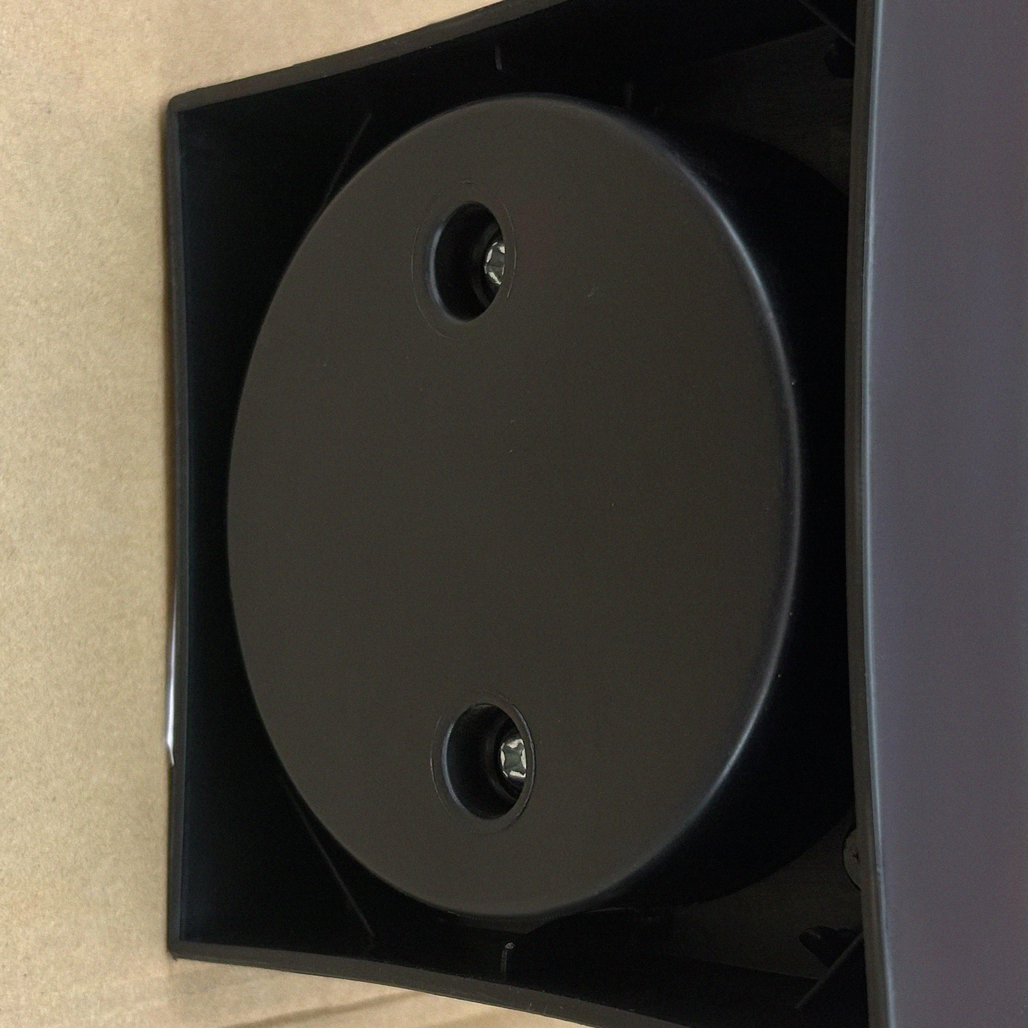 Primo piano di un altoparlante nero e cilindrico. Due viti sono visibili sulla superficie circolare.