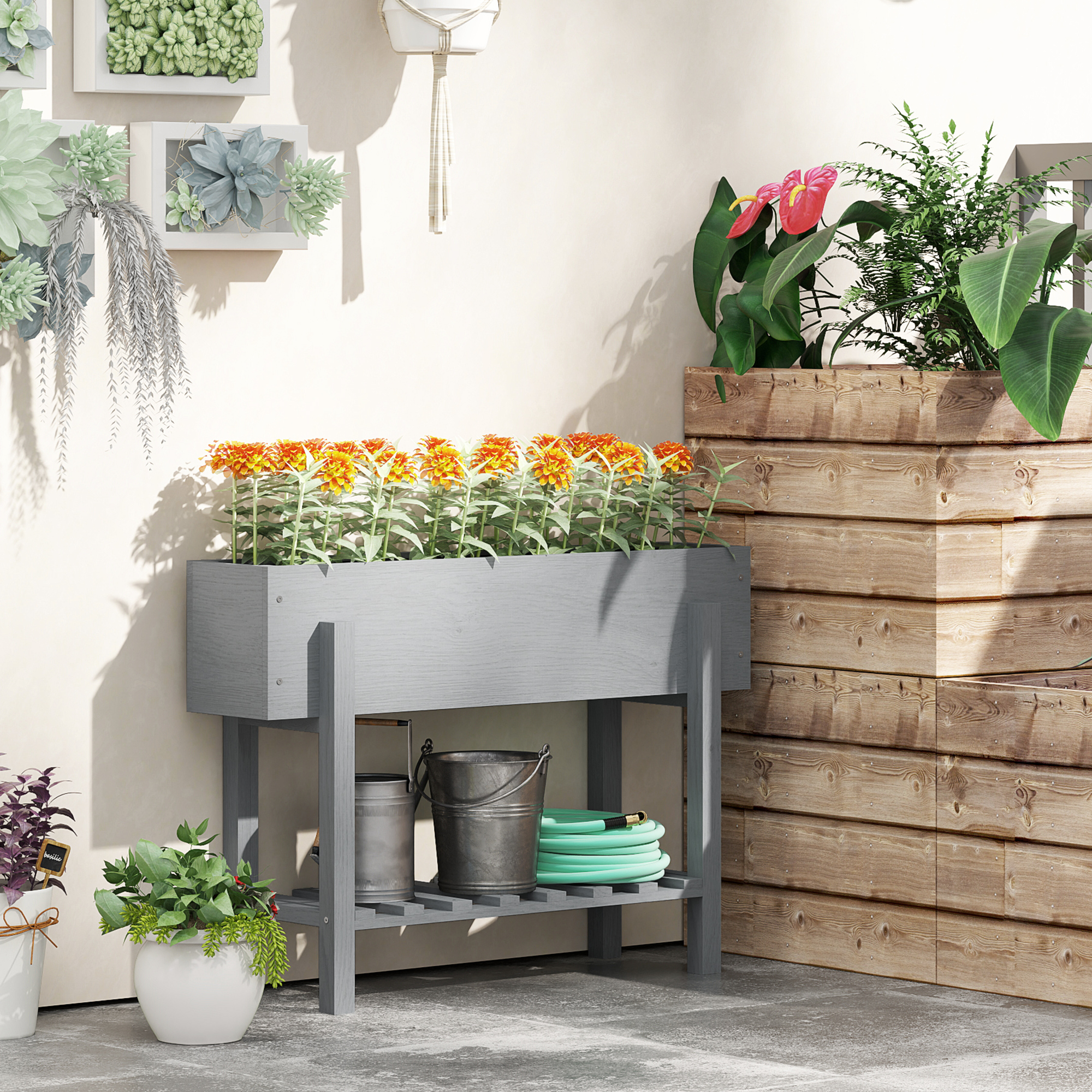 Una fioriera in legno grigio con fiori e un ripiano con attrezzi. Un'altra fioriera a destra.