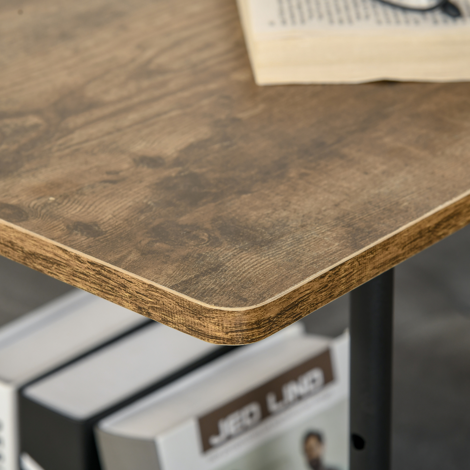 Primo piano di un angolo del tavolo in legno. Libro e occhiali visibili. Tavolo marrone con bordo dettagliato.